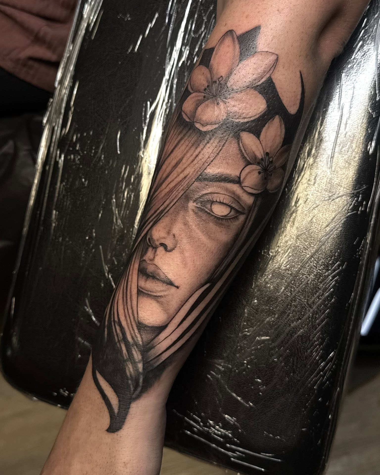 Woman's face with flowers realism tattoo on the forearm by Madison Jasso