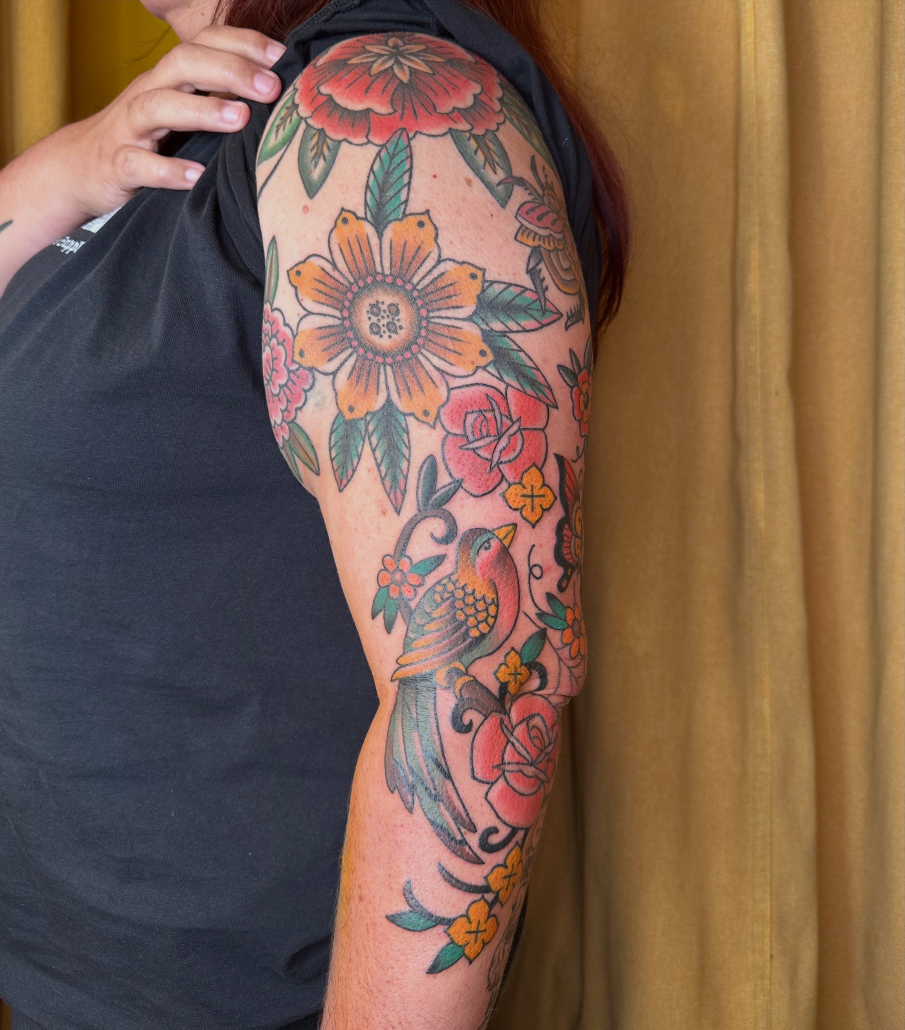 Floral and bird American traditional tattoo on the upper arm by Brieana Smith