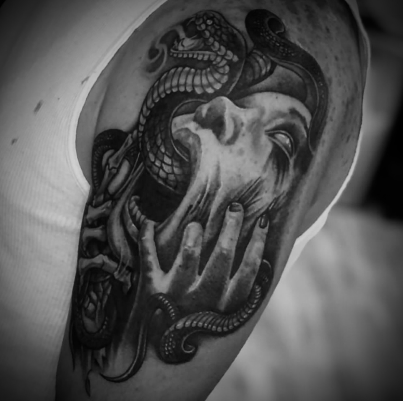 Snake and hands realism tattoo on the upper arm by Big Steve Lewis