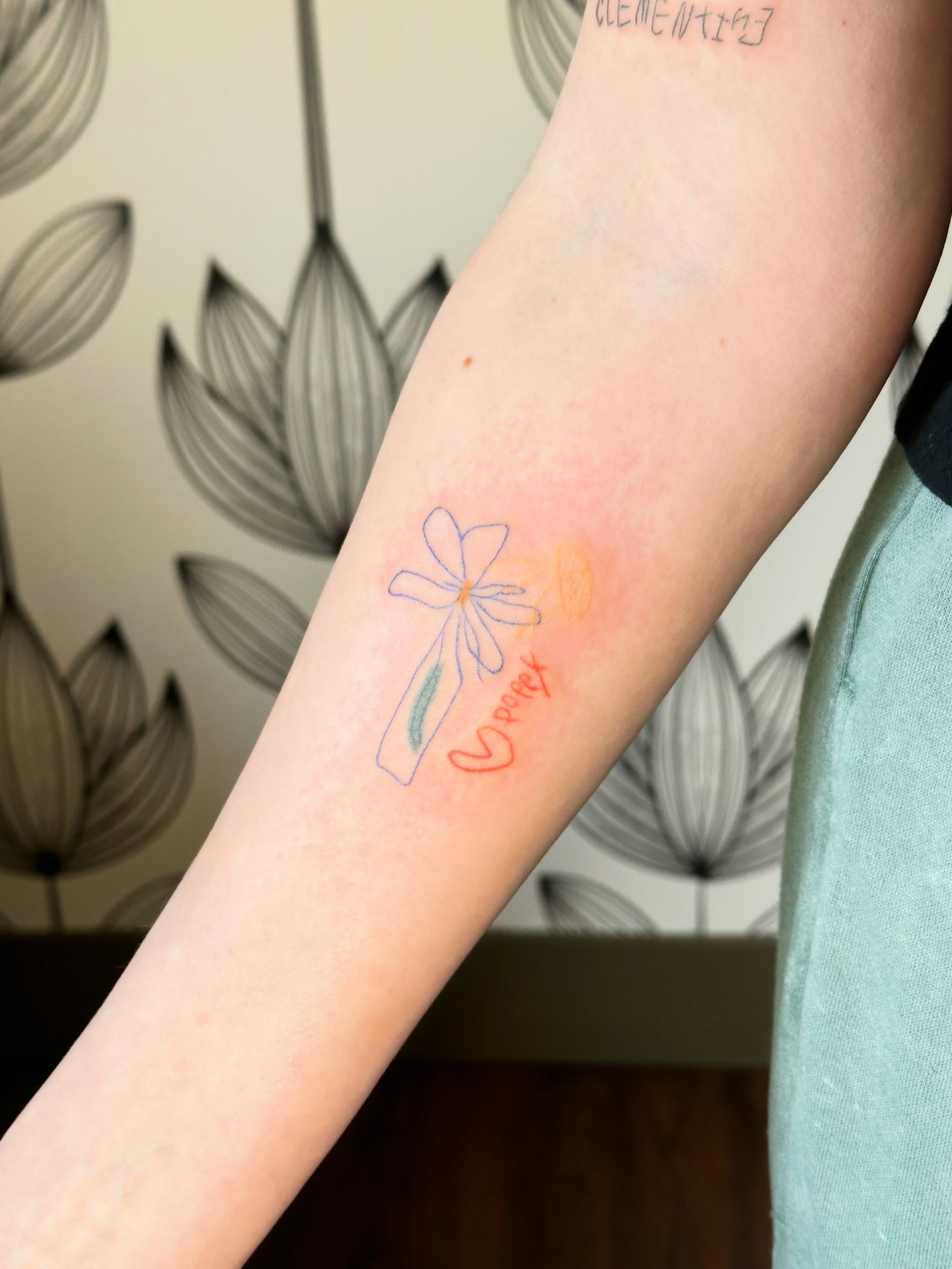 Flower and bottle watercolor tattoo on the forearm by Liz