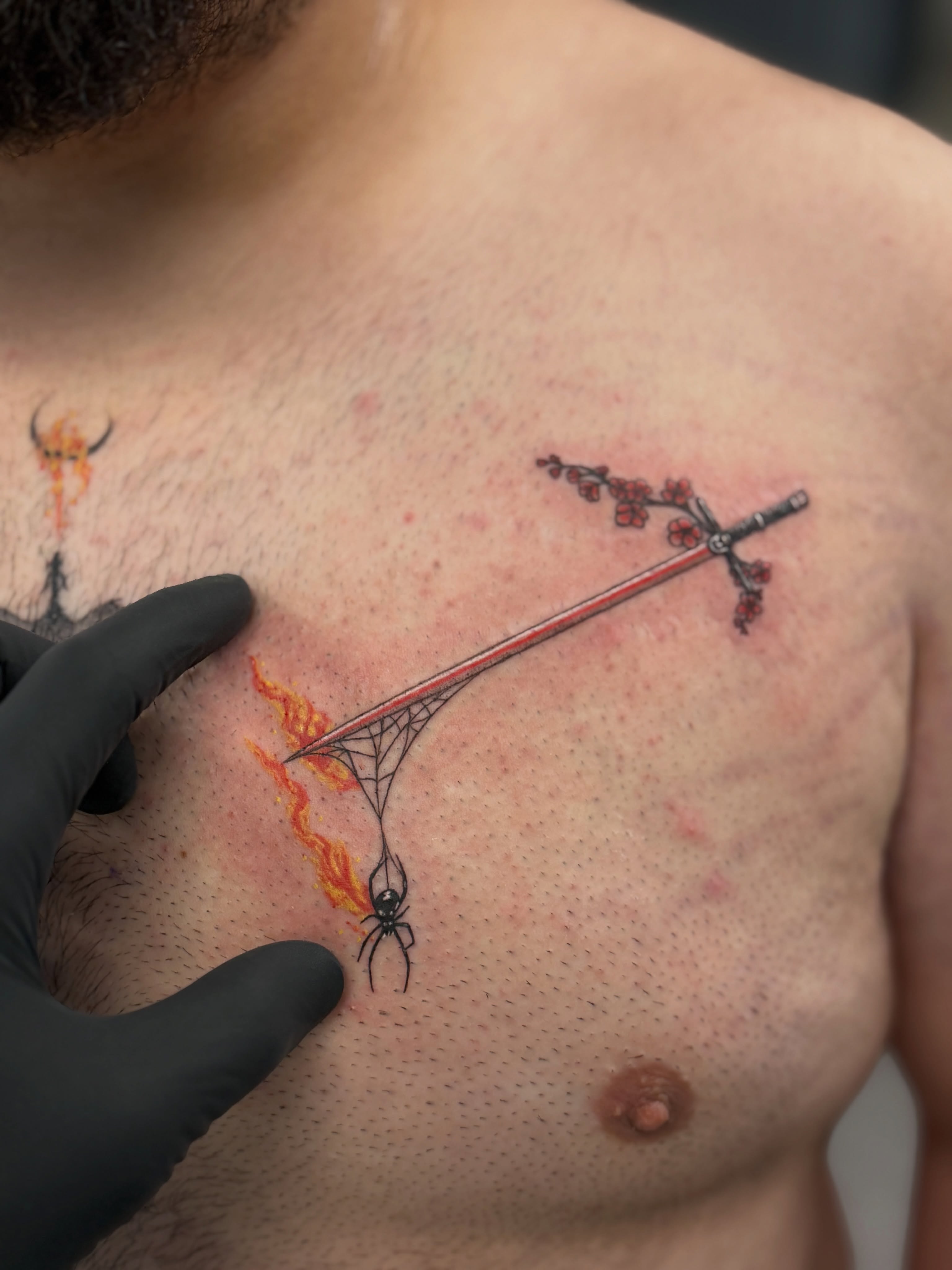 Sword and spider dotwork tattoo on the chest by Raciel Fabian Romero