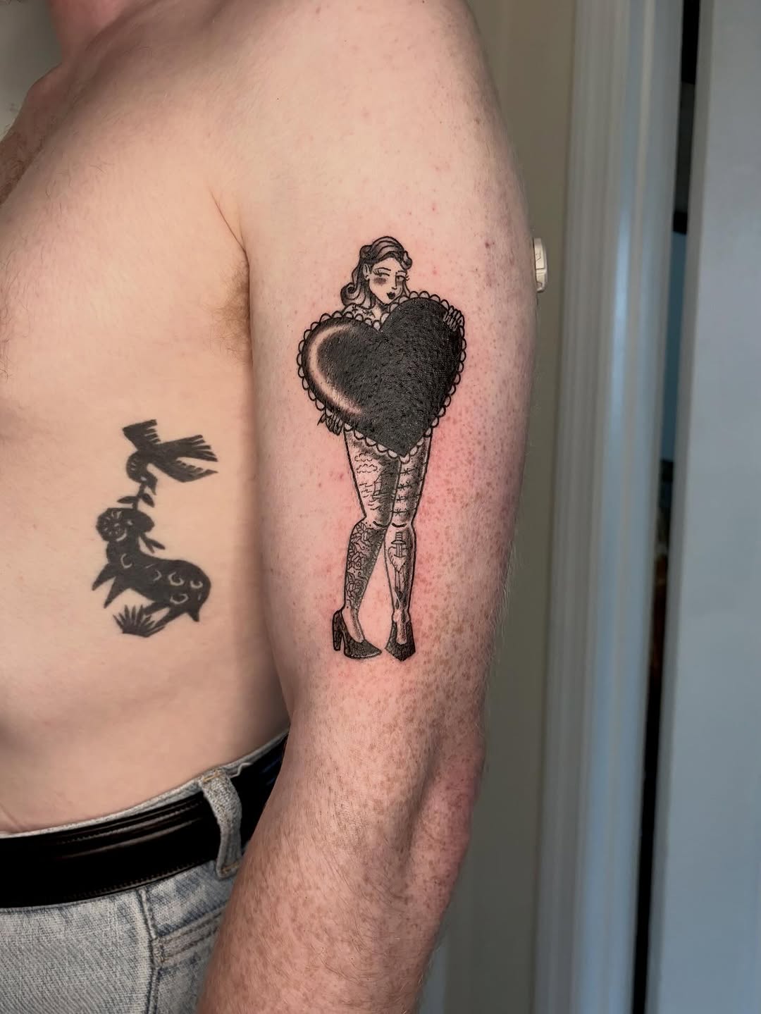 Pin-up girl holding heart minimalist tattoo on the upper arm by Fin :