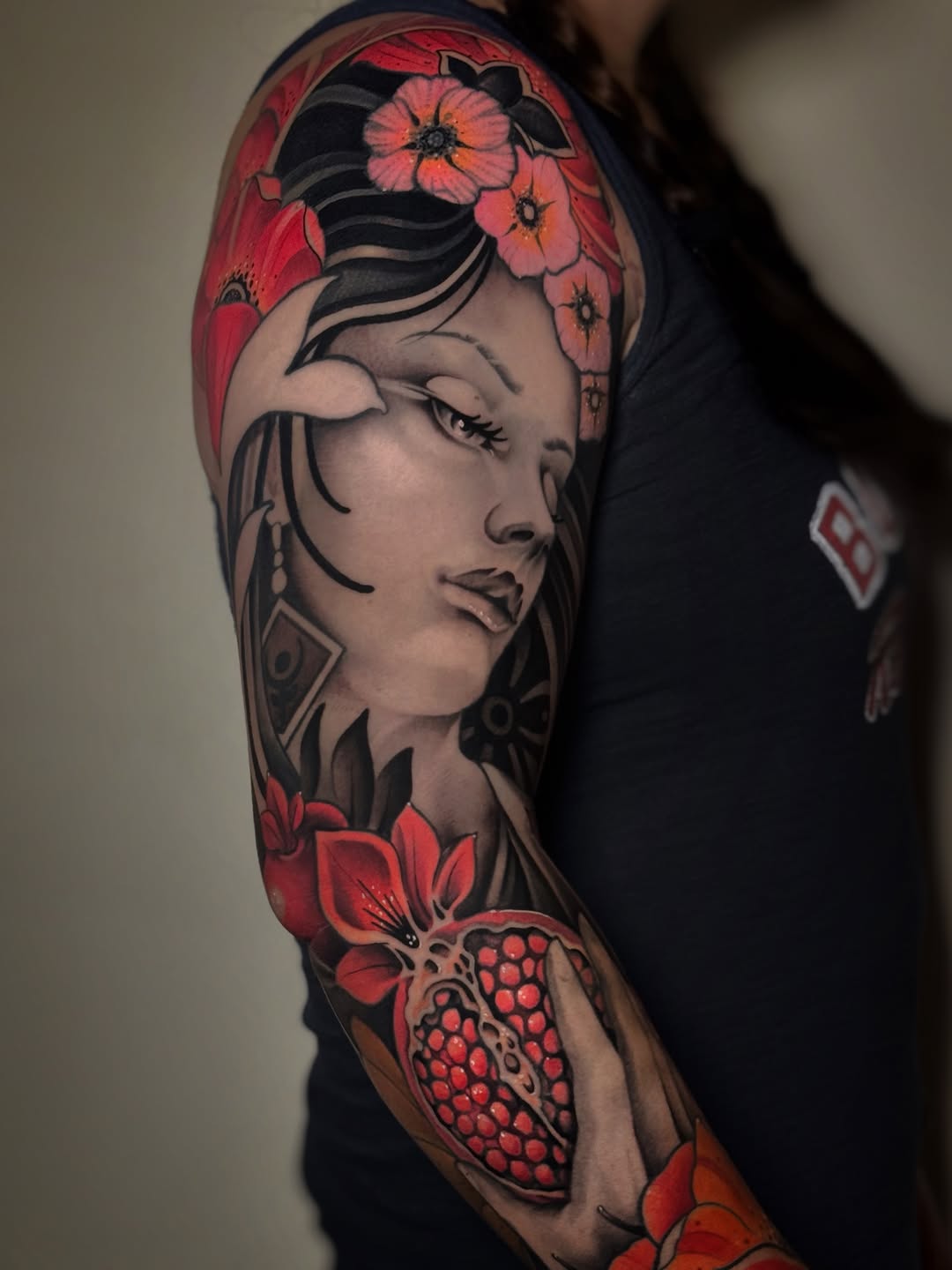 Woman with pomegranate and flowers realism tattoo on the upper arm by Aitor Arie, Roseville, California