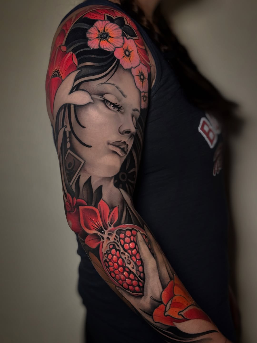 Woman holding a pomegranate realism tattoo on the upper arm by Aitor Arie, Roseville, California