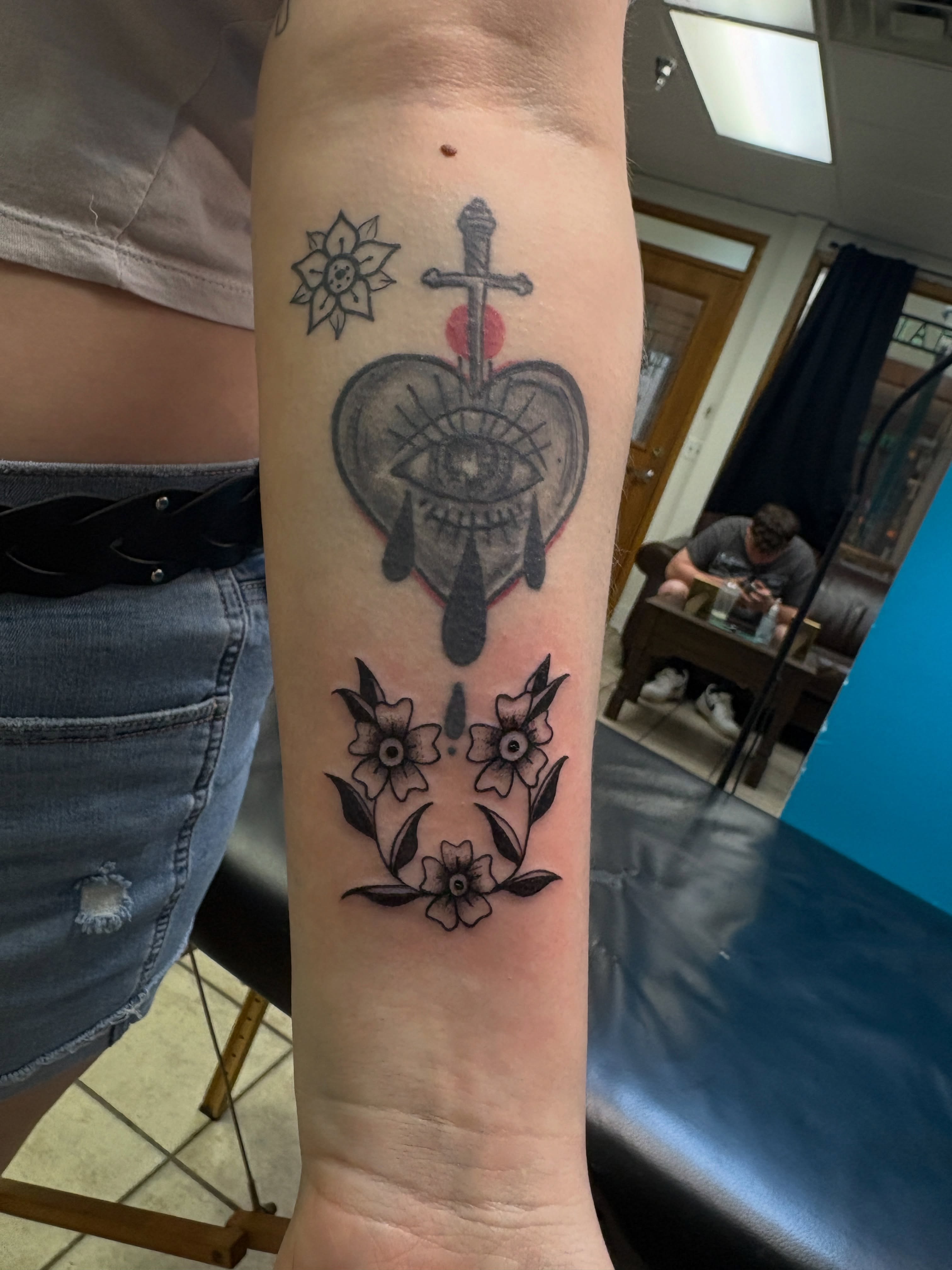 Heart with eye and dagger black and grey tattoo on the forearm by ⋆.˚ ☾ .⭒˚ alaina