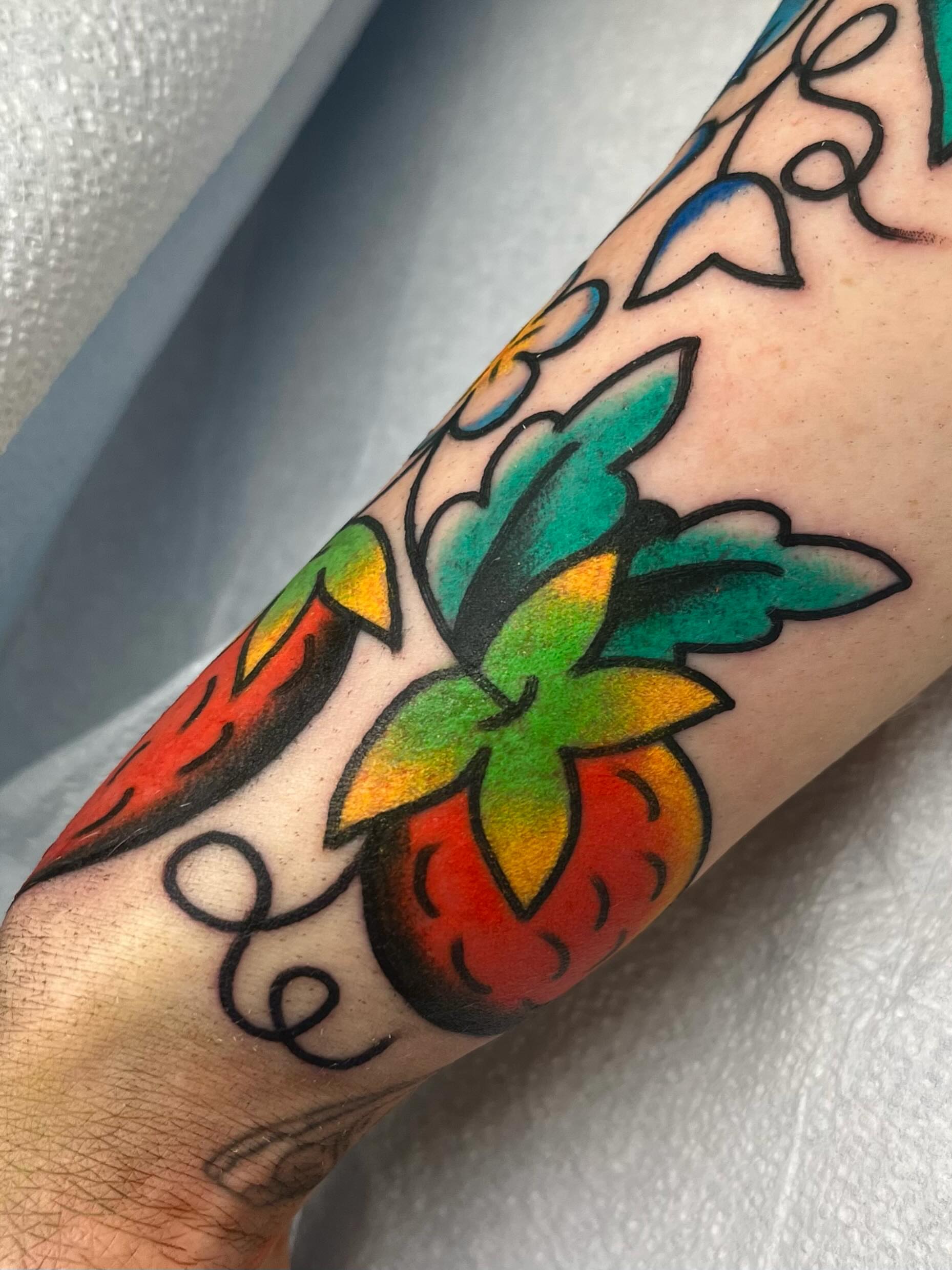Strawberry American traditional tattoo on the forearm by Em Adkins