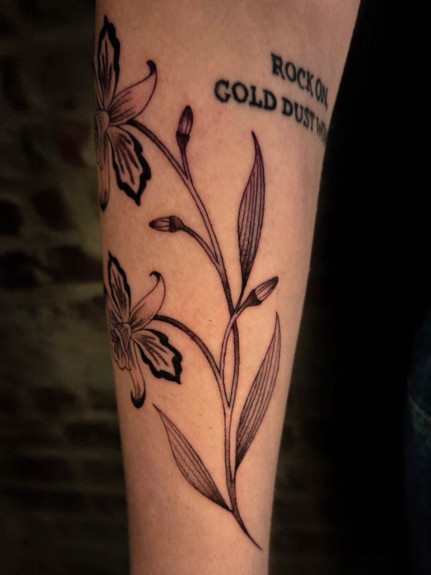 Orchids and leaves black and grey tattoo on the forearm by Ian Kiser