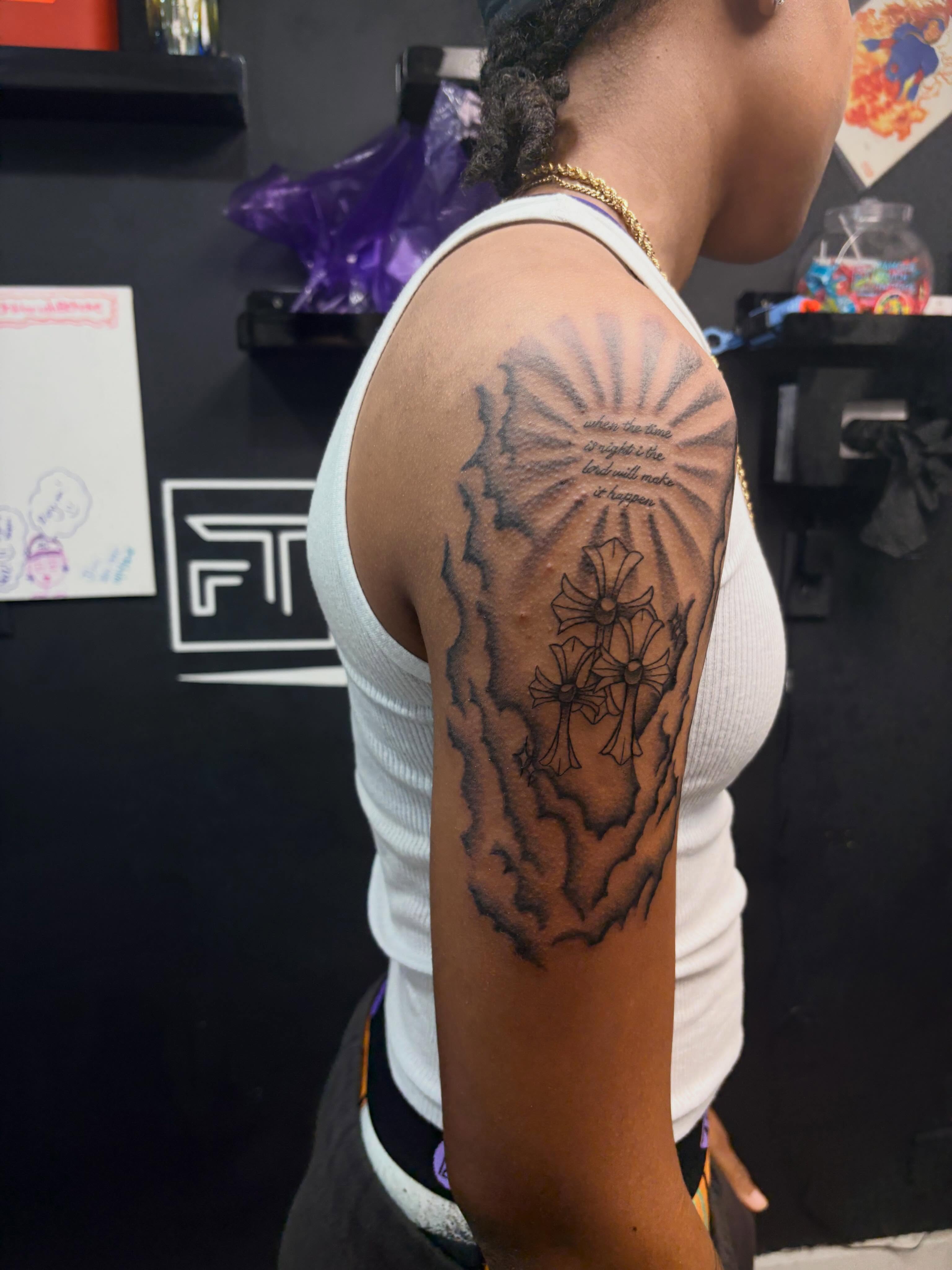 Crosses and flowers black and grey tattoo on the upper arm by 𝓚𝓪𝓻𝓶𝓪💫