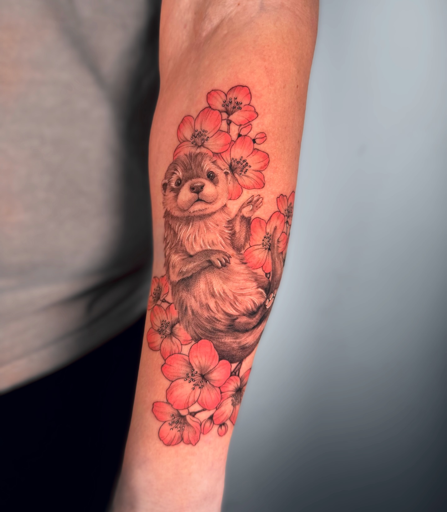 Otter and flowers realism tattoo on the forearm by Cyn