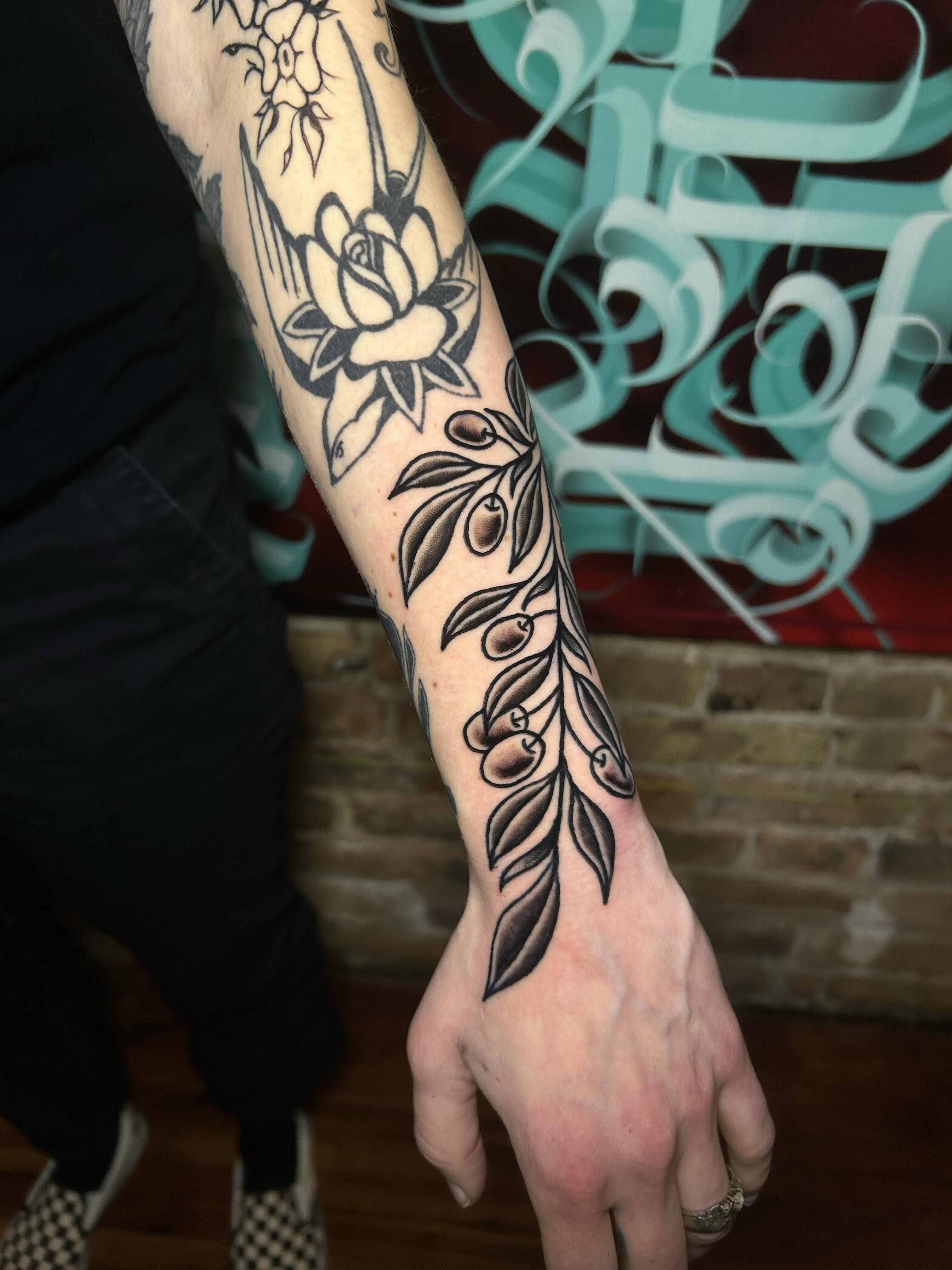 Olive branch and flower American traditional tattoo on the forearm by Alycia