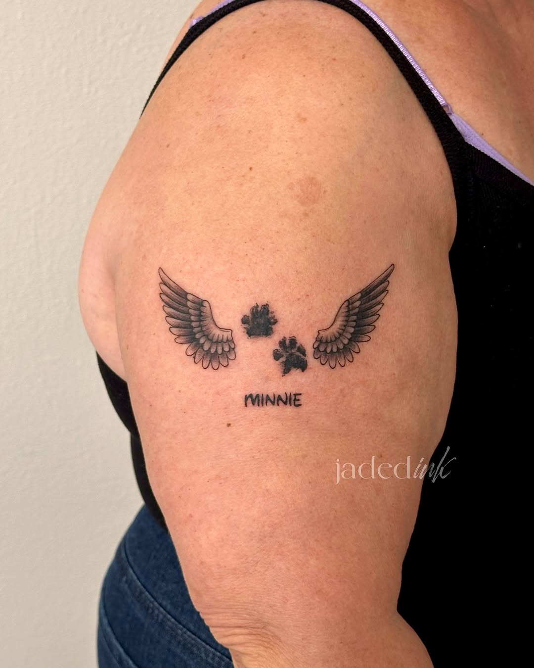 Wings with paw prints and name realism tattoo on the shoulder by 𝑱𝒂𝒅𝒆𝒅 𝑰𝒏𝒌 𝑷𝒆𝒓𝒎𝒂𝒏𝒆𝒏𝒕 𝑴𝒂𝒌𝒆𝒖𝒑 & 𝑻𝒂𝒕𝒕𝒐𝒐