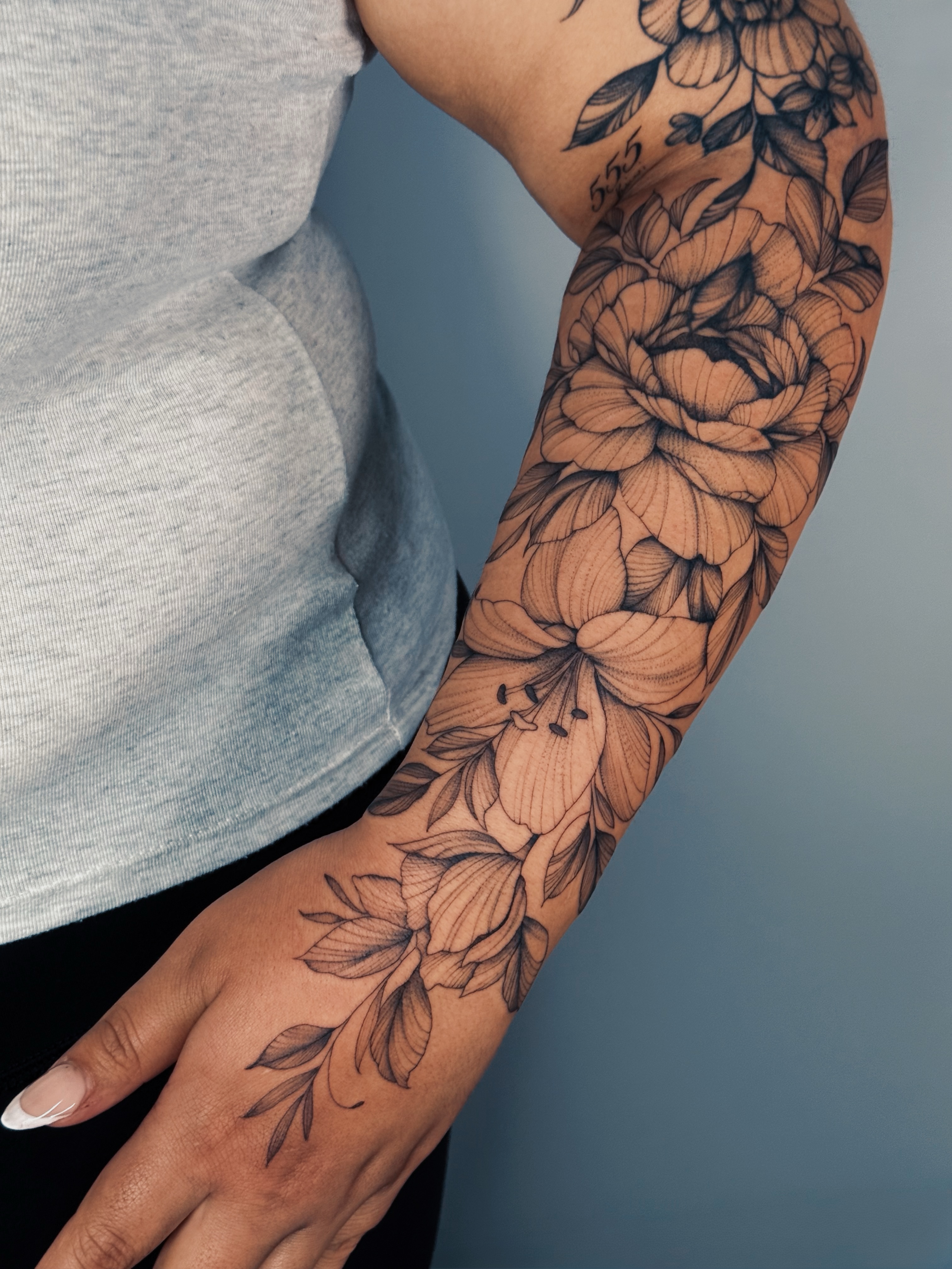 Floral bouquet black and grey tattoo on the forearm by Olha Tytarenko