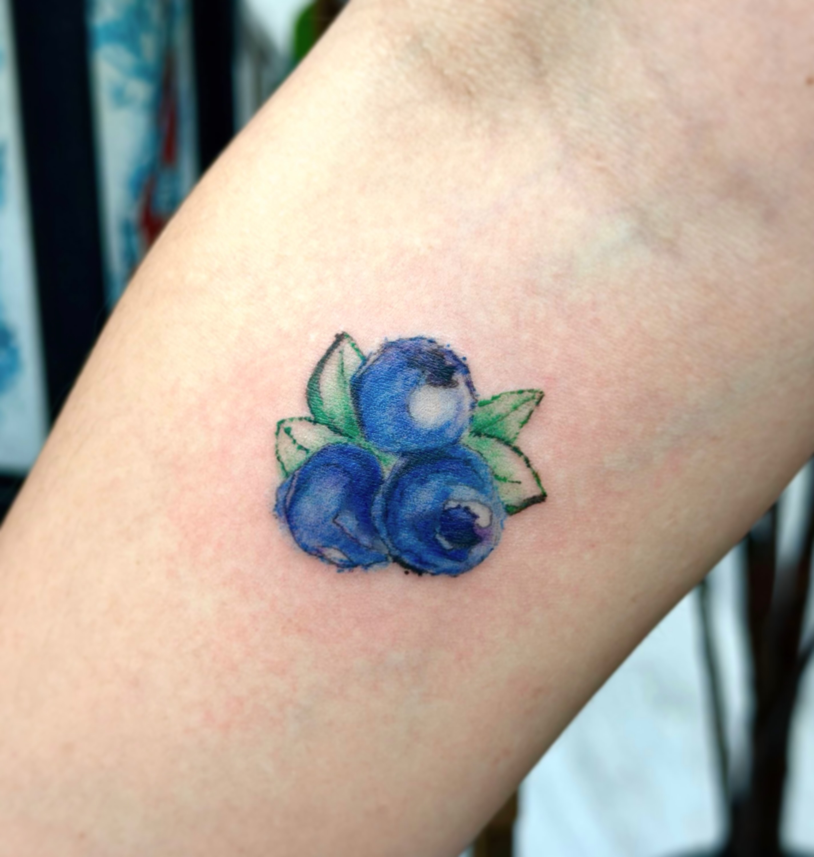 Blueberries watercolor tattoo on the forearm by Xin Huang