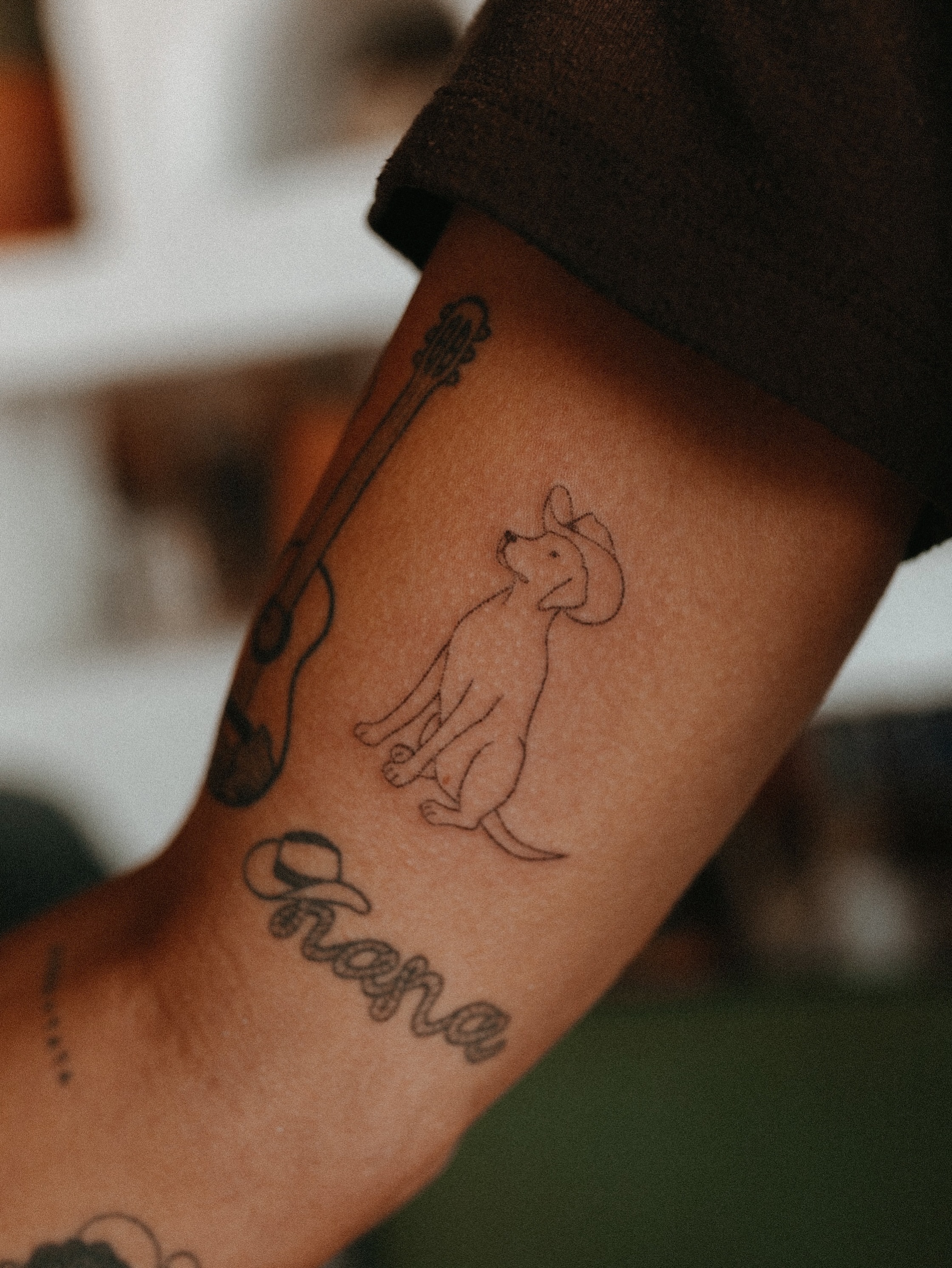 Dog with guitar fine line tattoo on the forearm by Grace Wise - Handpoke Tattoos