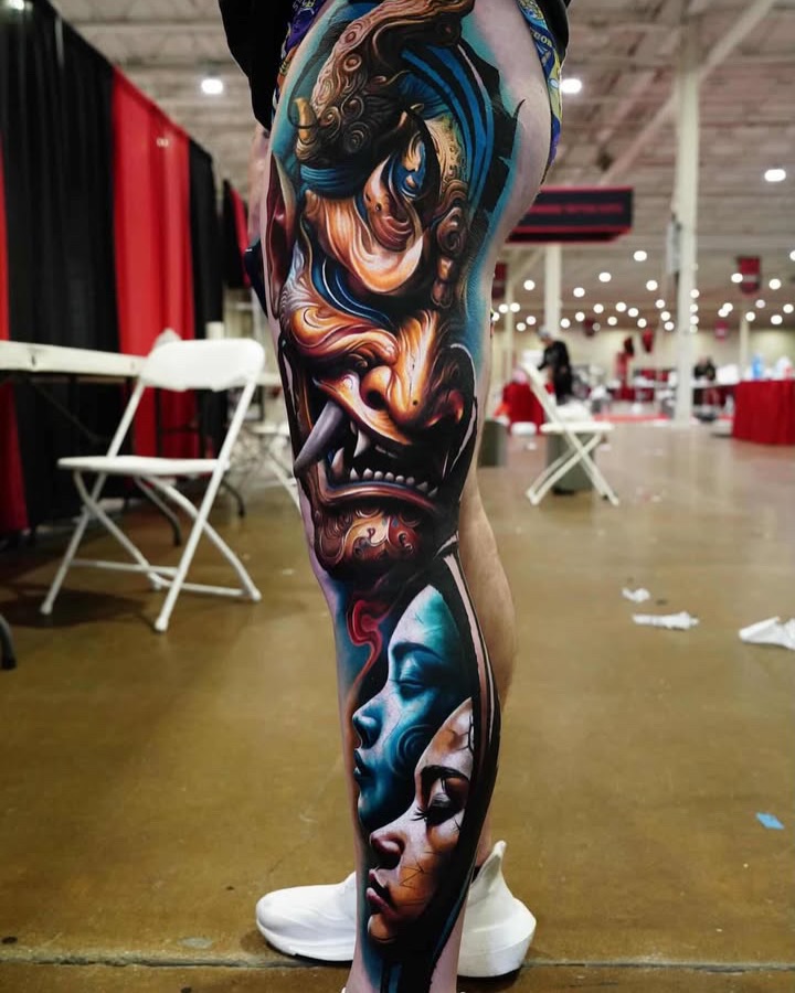 Oni mask and faces surrealism tattoo on the leg by Guillermo Columbie, Houston, Texas