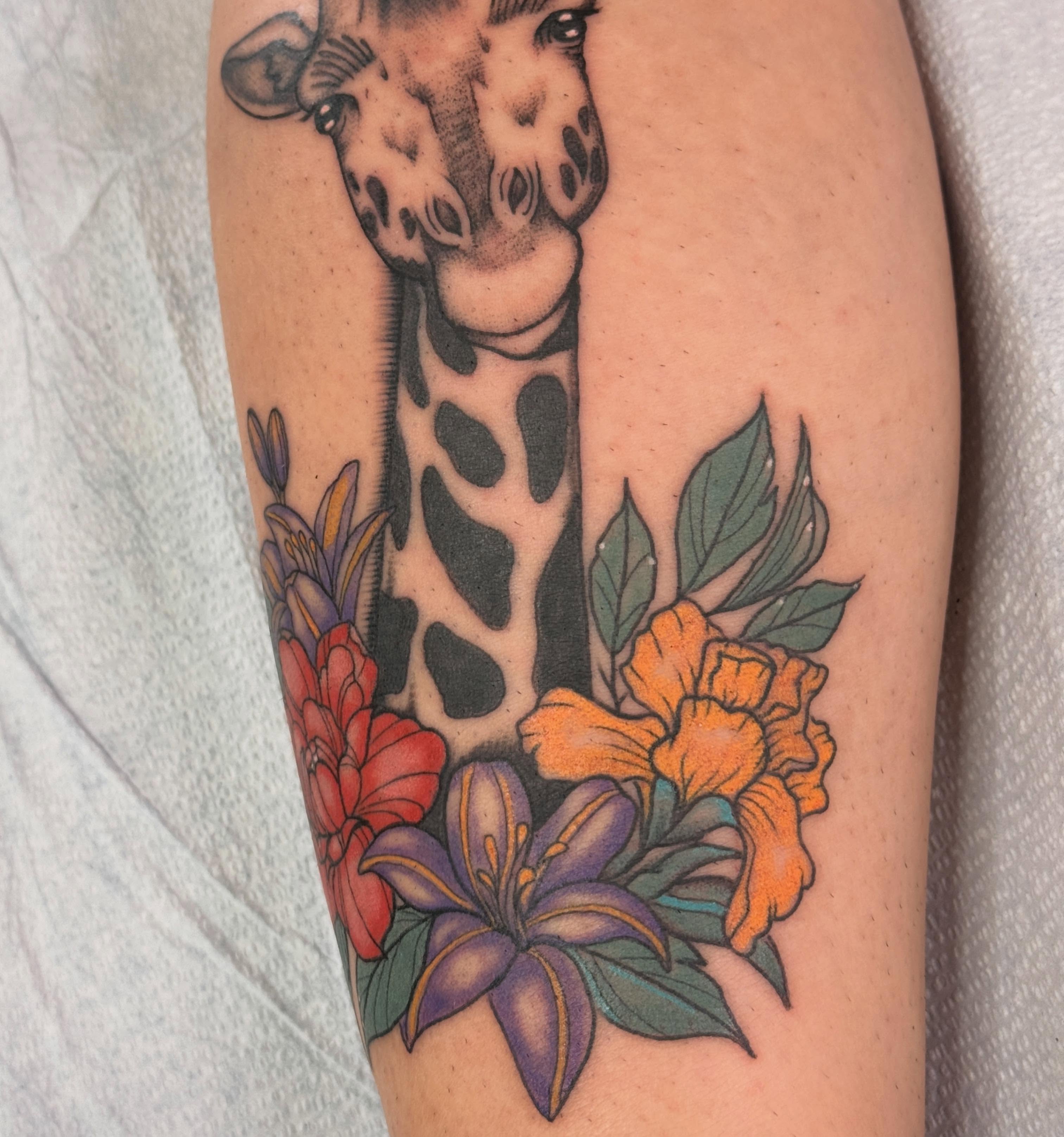 Giraffe and flowers realism tattoo on the forearm by Megan Sue Causemaker