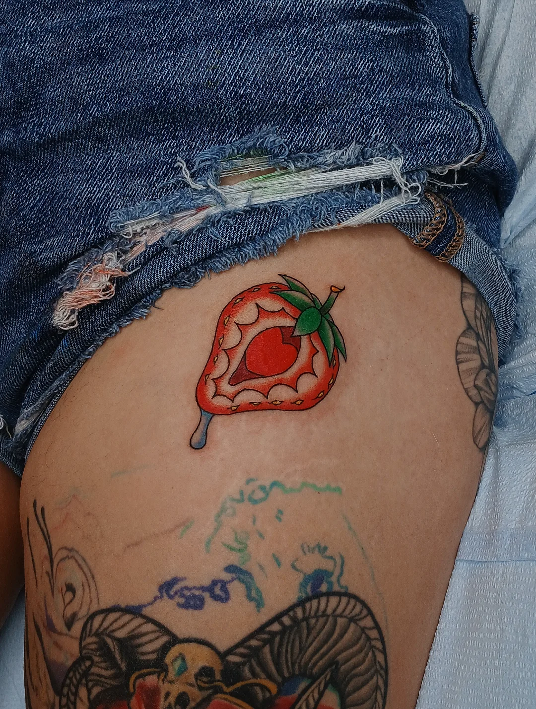 Strawberry new school tattoo on the thigh by Amber Tattoos