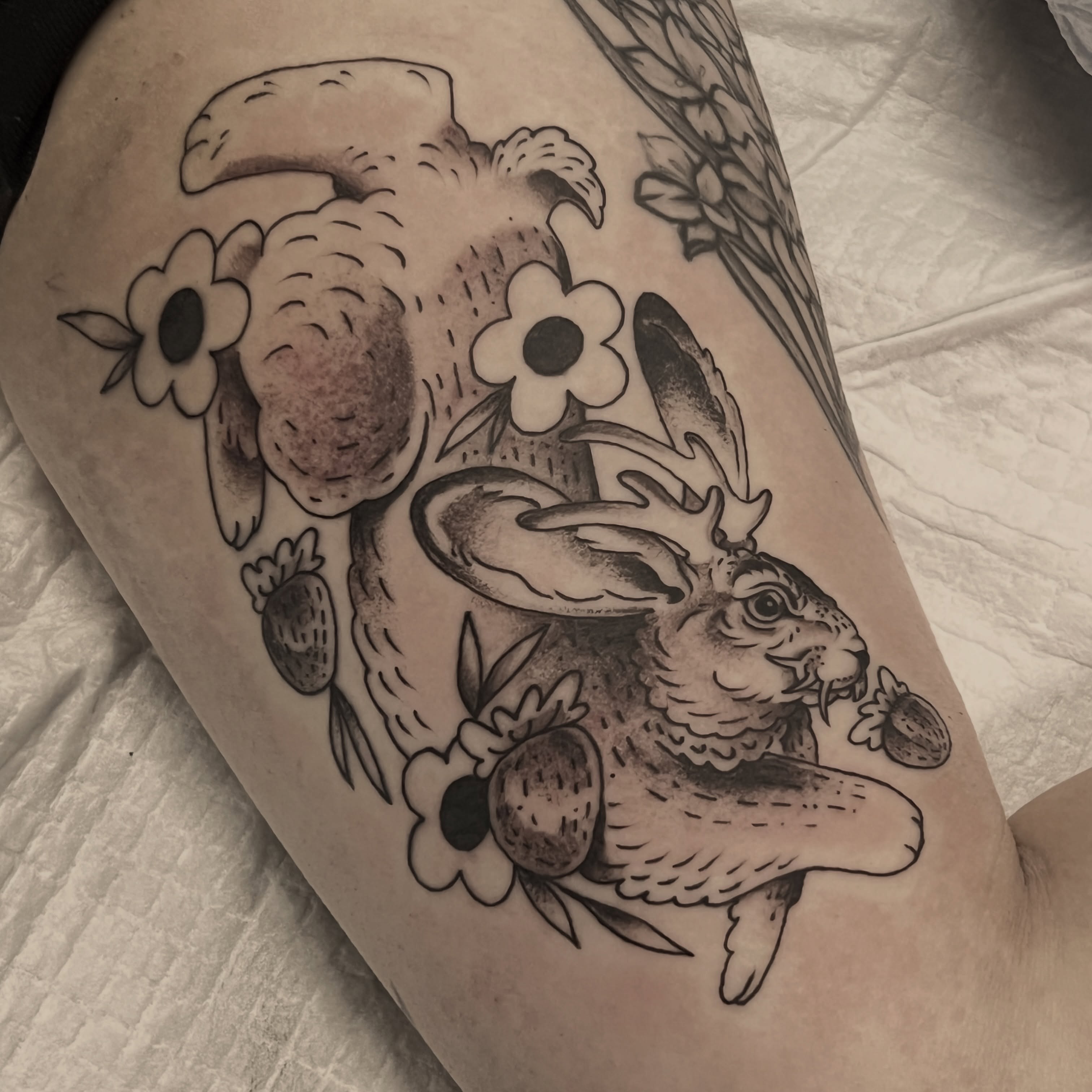 Rabbit and flowers realism tattoo on the thigh by Andrea Patterson
