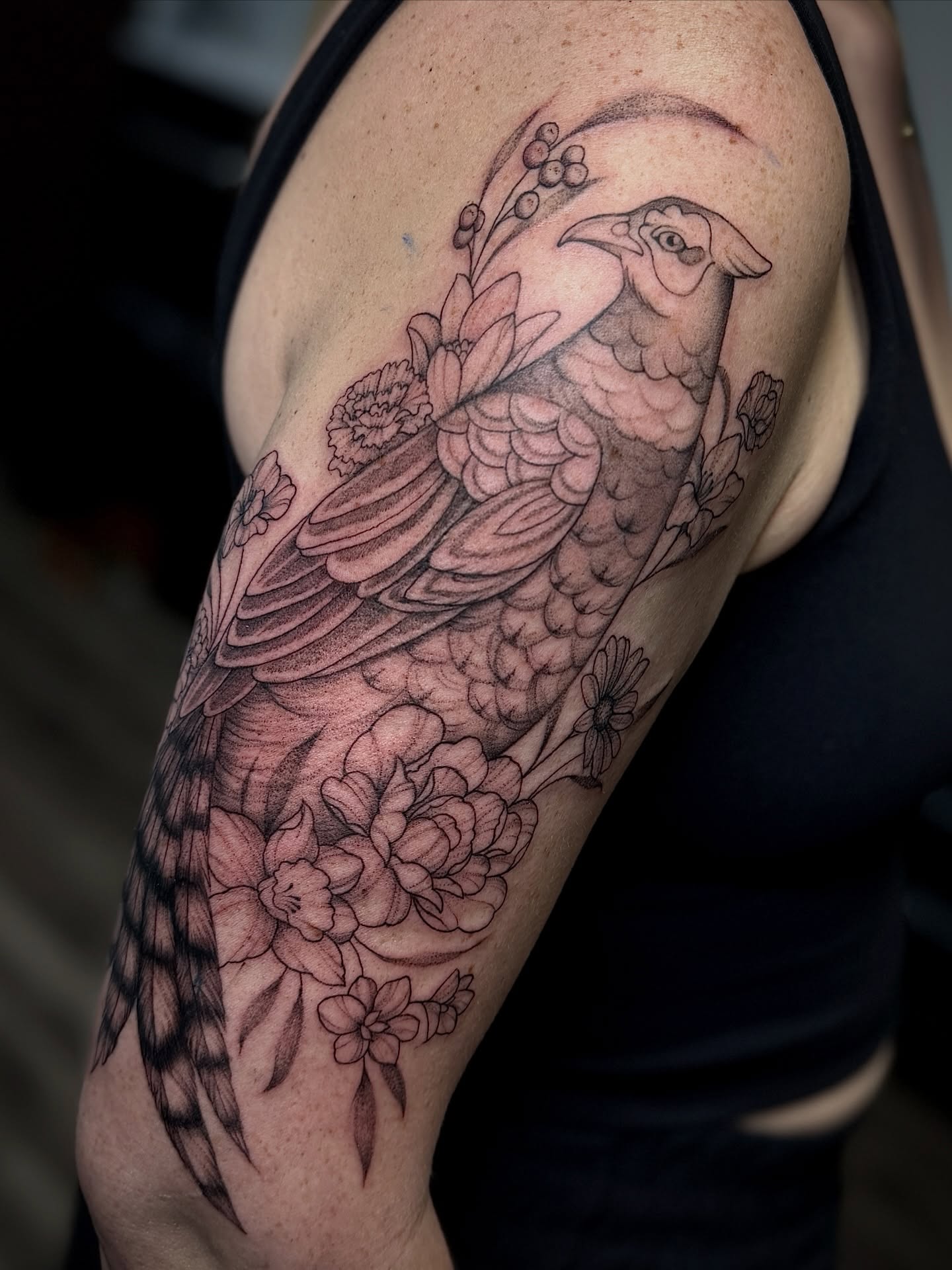 Bird and floral realism tattoo on the upper arm by 𝐀𝐝𝐫𝐢𝐞𝐥 𝐓𝐢𝐧𝐤𝐥𝐞𝐧𝐛𝐞𝐫𝐠 ⏾, Denison, Iowa