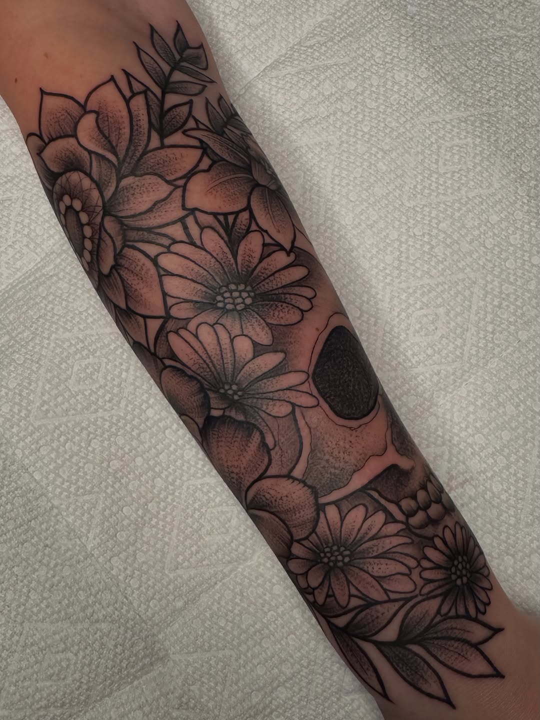 Skull and flowers dotwork tattoo on the forearm by Lisa Nikolopoulos, New York, New York