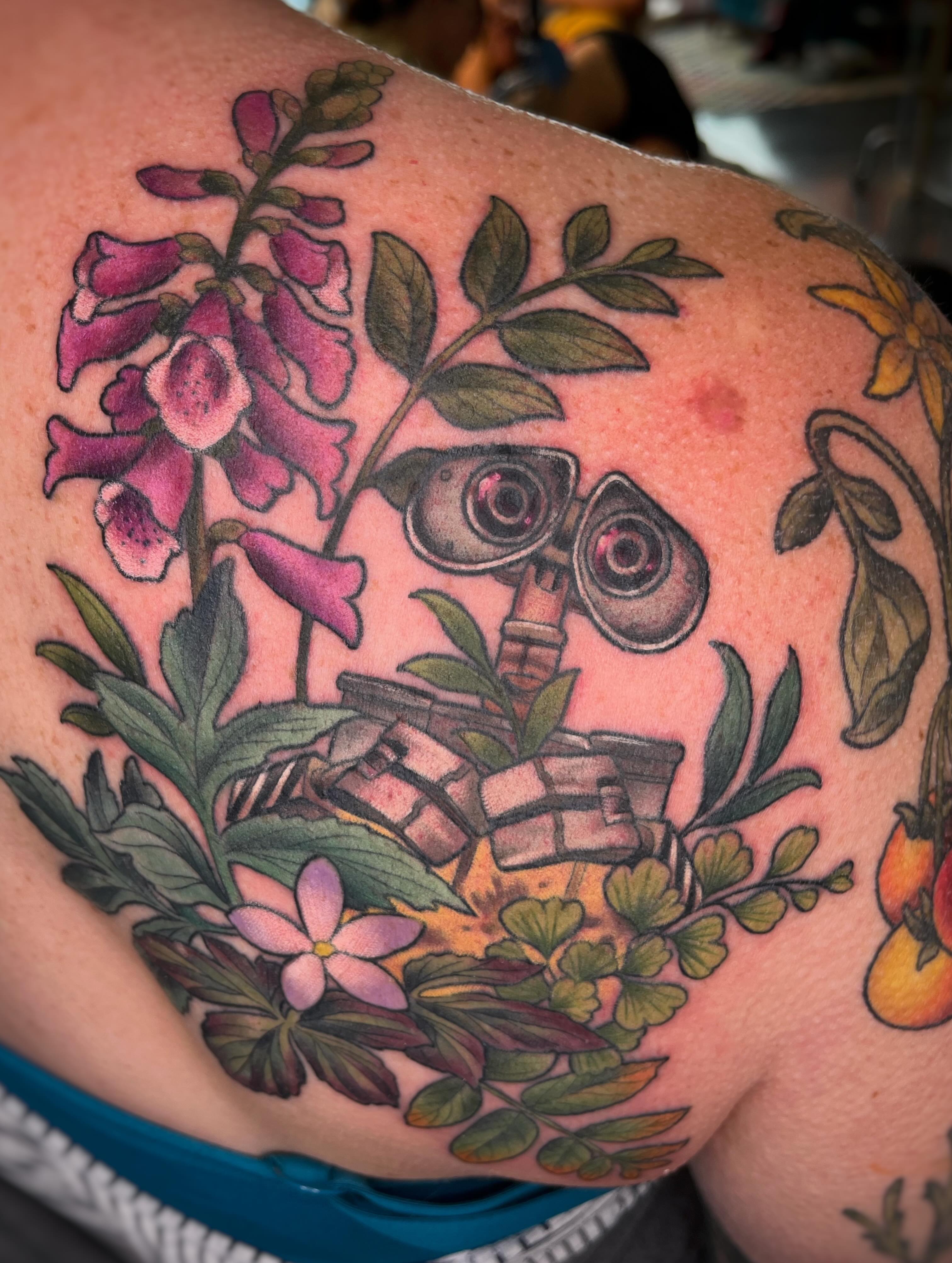 Wall-e and floral realism tattoo on the shoulder by Emi Collison