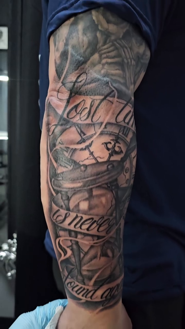 Compass and clock with lettering Chicano tattoo on the forearm by Mac Obaob