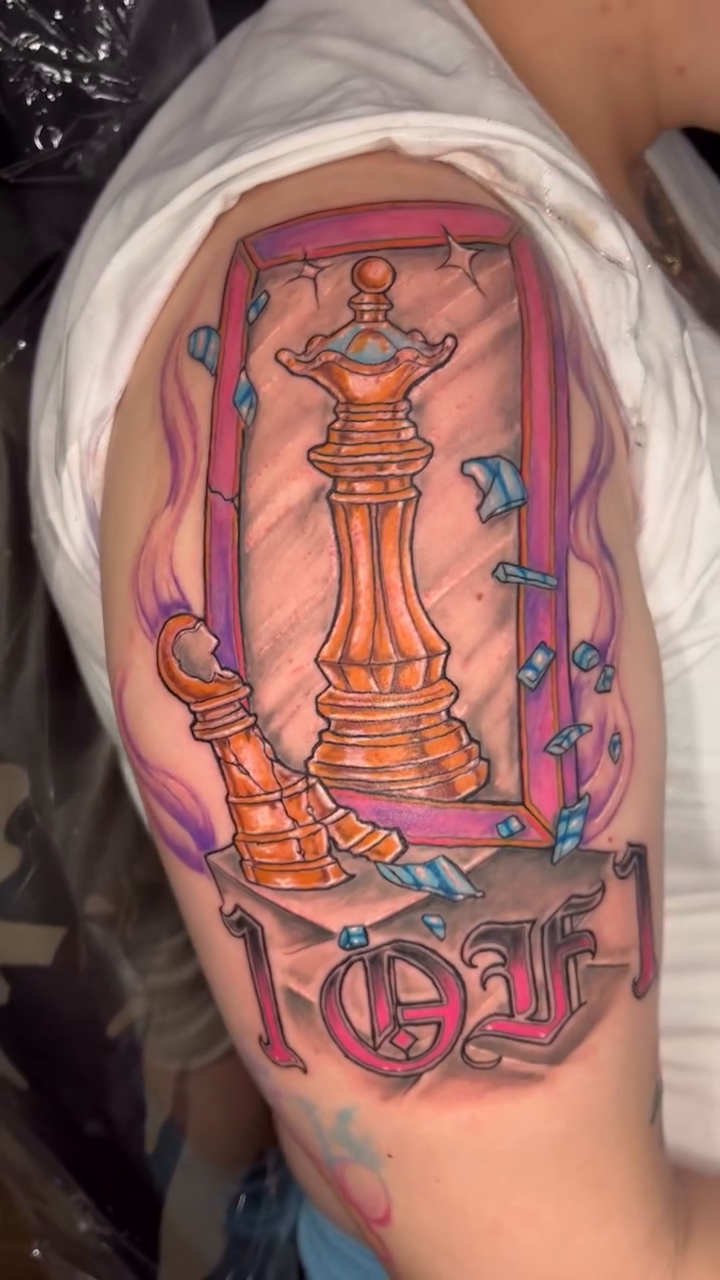 Chess queen and king with lettering realism tattoo on the upper arm by Jakobi