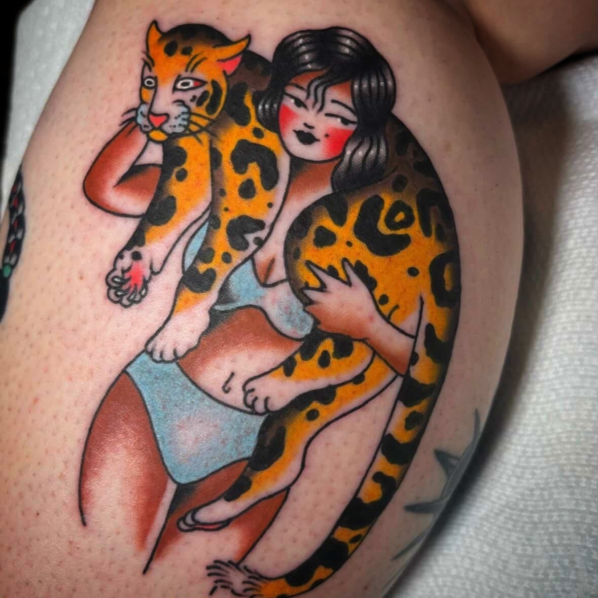 Woman with leopard American traditional tattoo on the thigh by Caeli Martin