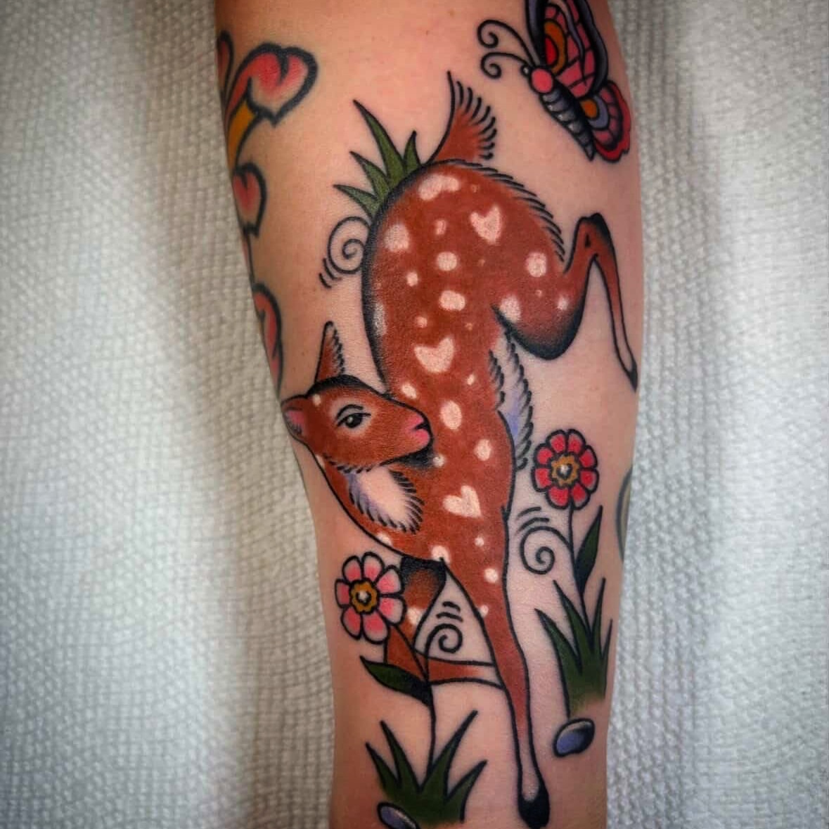 Deer and flowers American traditional tattoo on the forearm by Caeli Martin