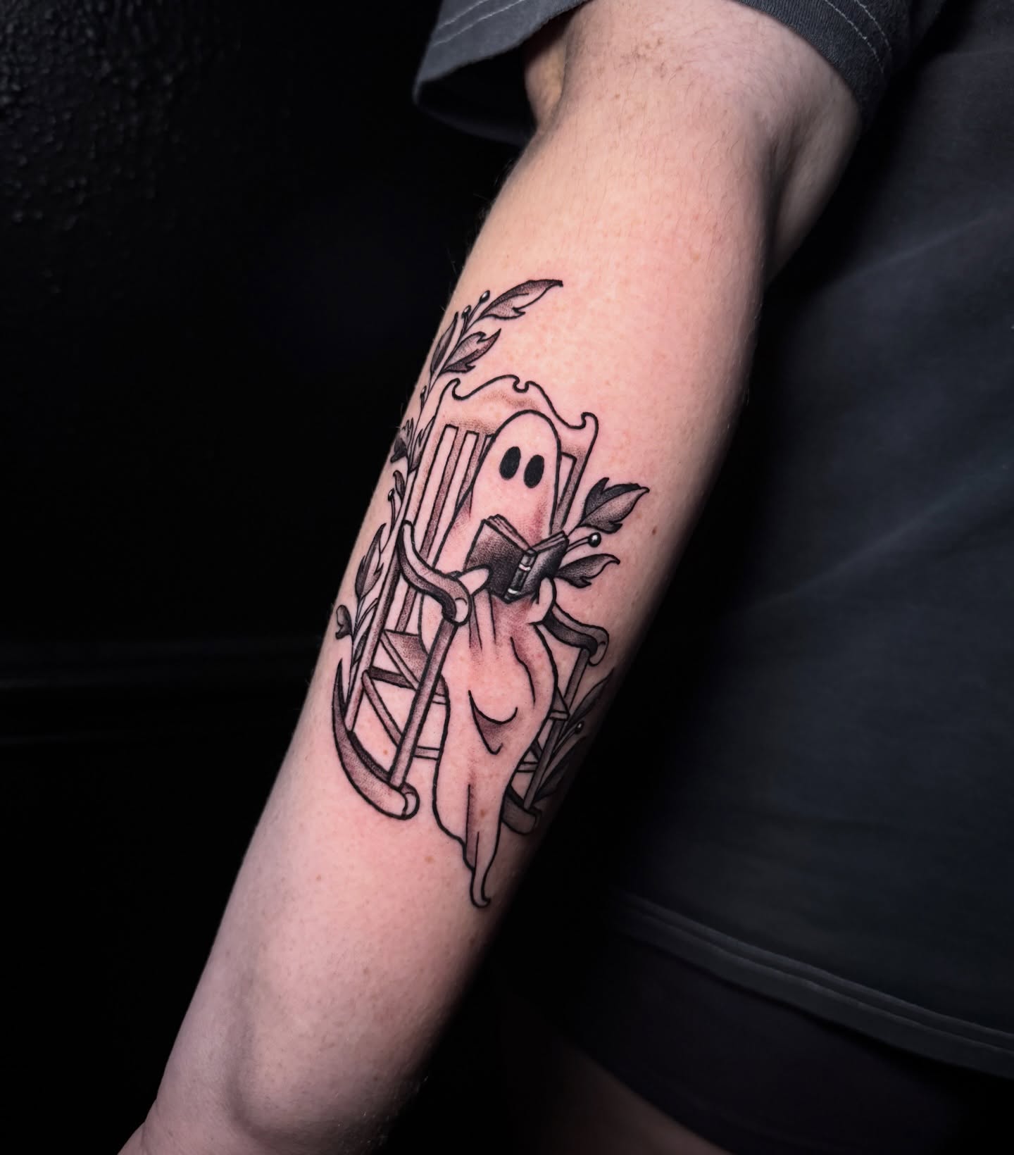 Ghost reading book black and grey tattoo on the forearm by Dee Florian