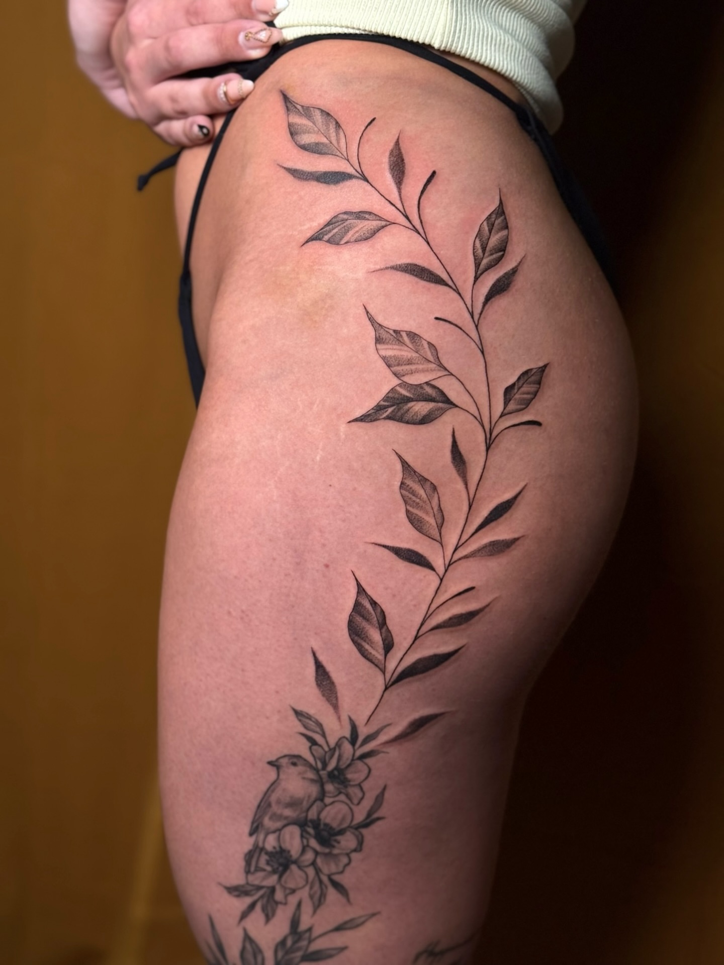 Branch with leaves and flowers black and grey tattoo on the thigh by Alyssa Fazzino ⟡ CT Tattoo Artist, Rocky Hill, Connecticut