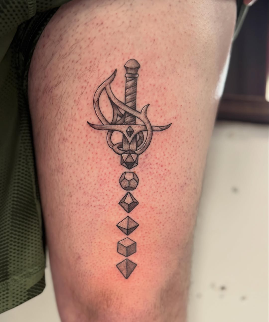 Sword and polyhedral dice sketch tattoo on the thigh by Felicity