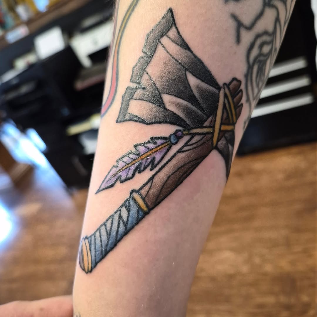 Axe with feather American traditional tattoo on the forearm by Bobby H