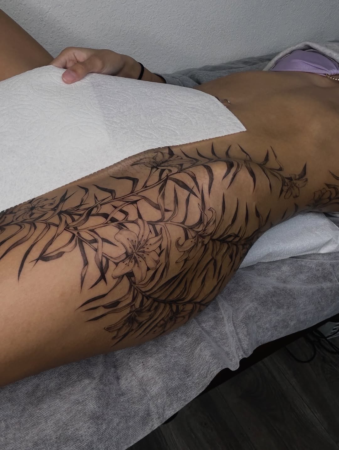 Floral pattern with lilies fine line tattoo on the thigh by Miri