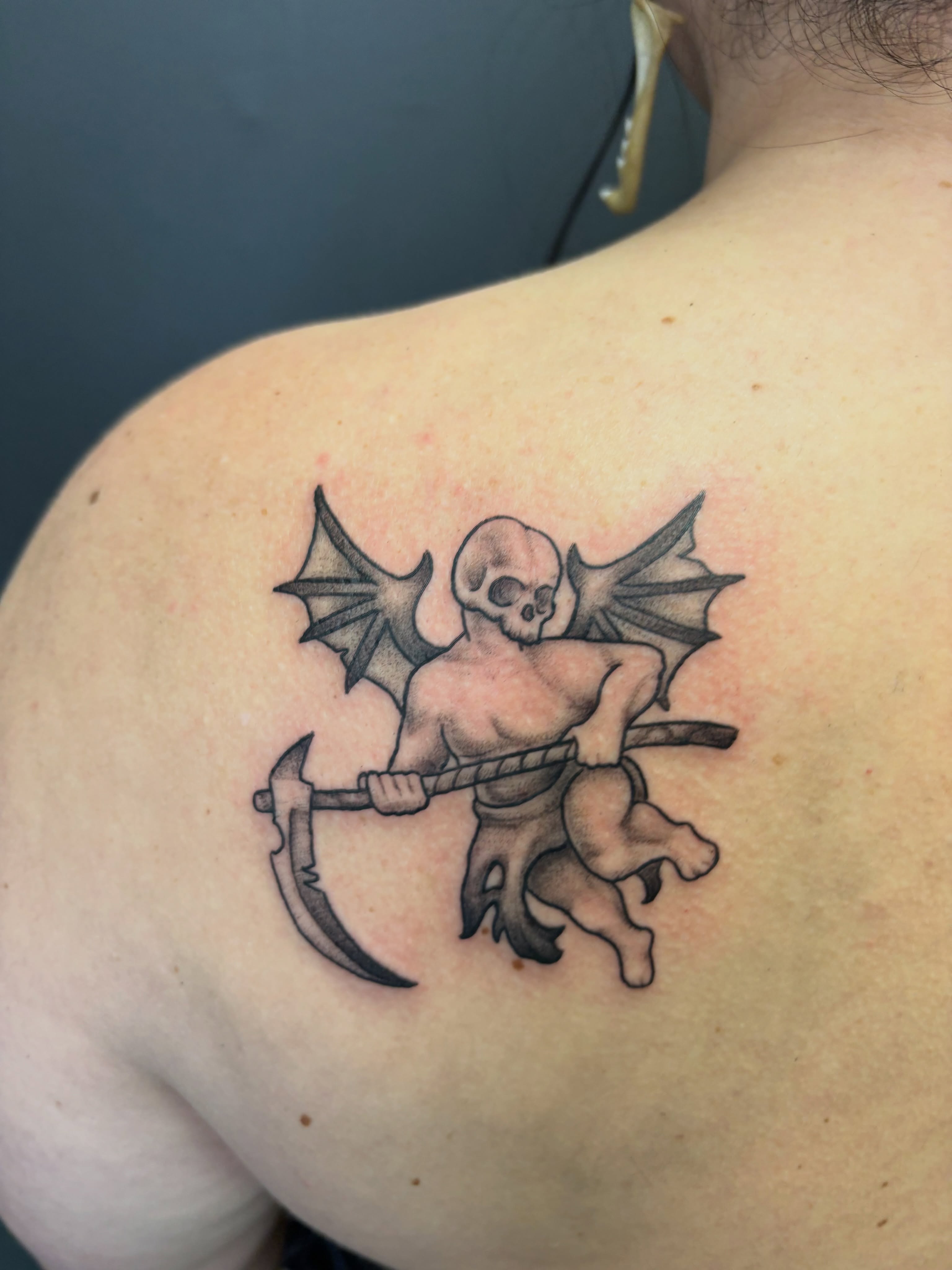Demons with scythe black and grey tattoo on the shoulder by Noah Blum