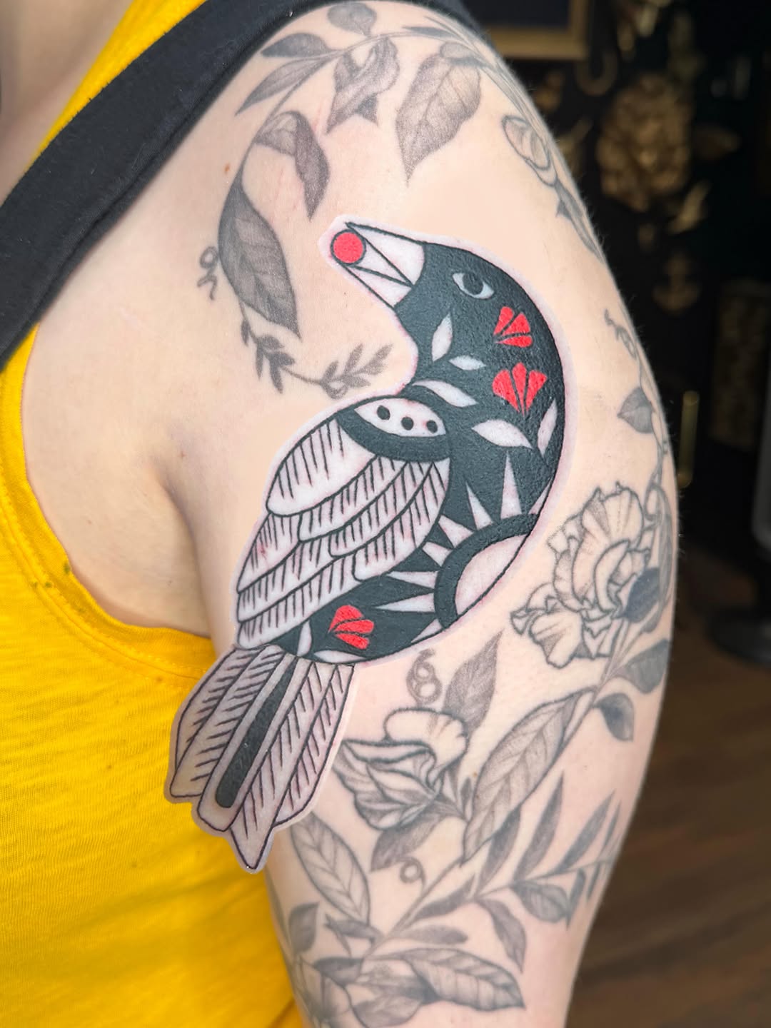 Stylized bird with floral elements fine line tattoo on the shoulder by Bri ⚡️✨