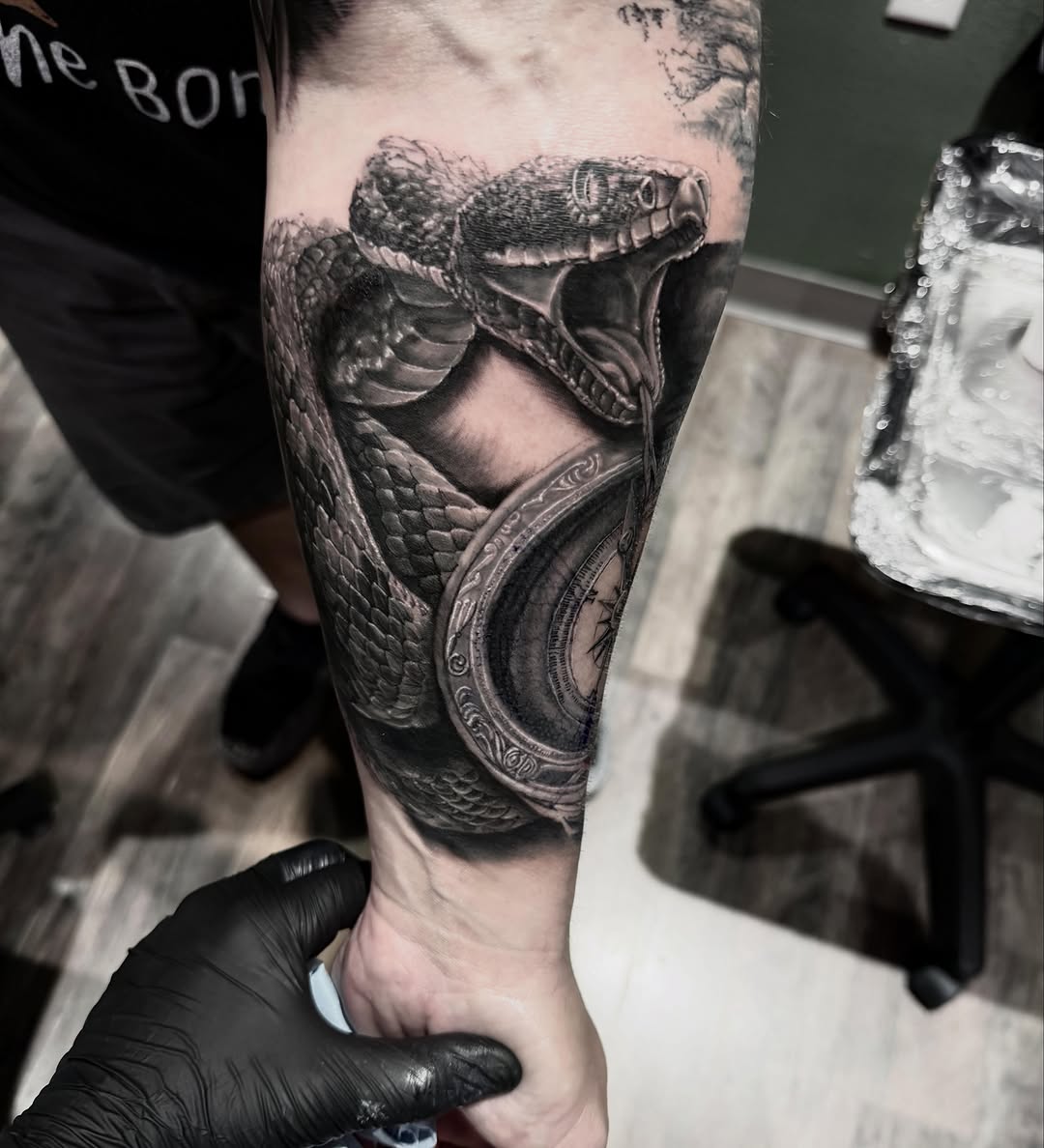 Snake and compass surrealism tattoo on the forearm by Blake Van Vleck