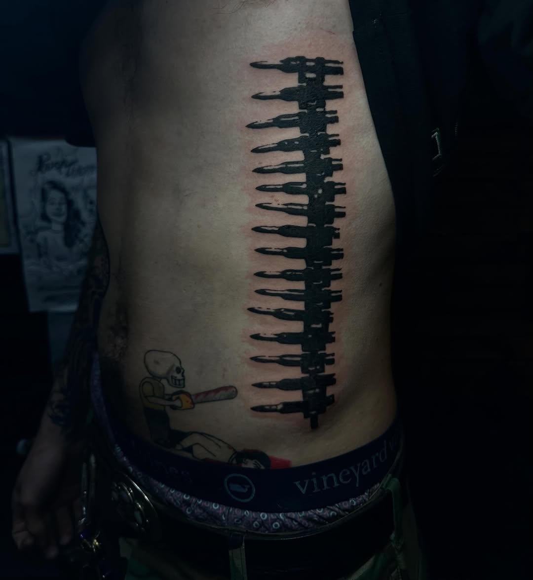 Ammunition belt ignorant tattoo on the ribs by emma christine