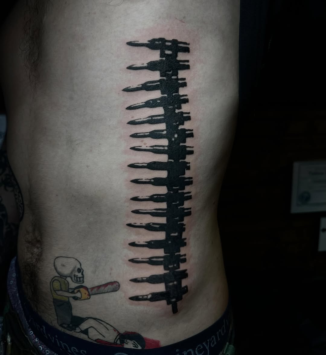 Bullet belt ignorant tattoo on the ribs by emma christine