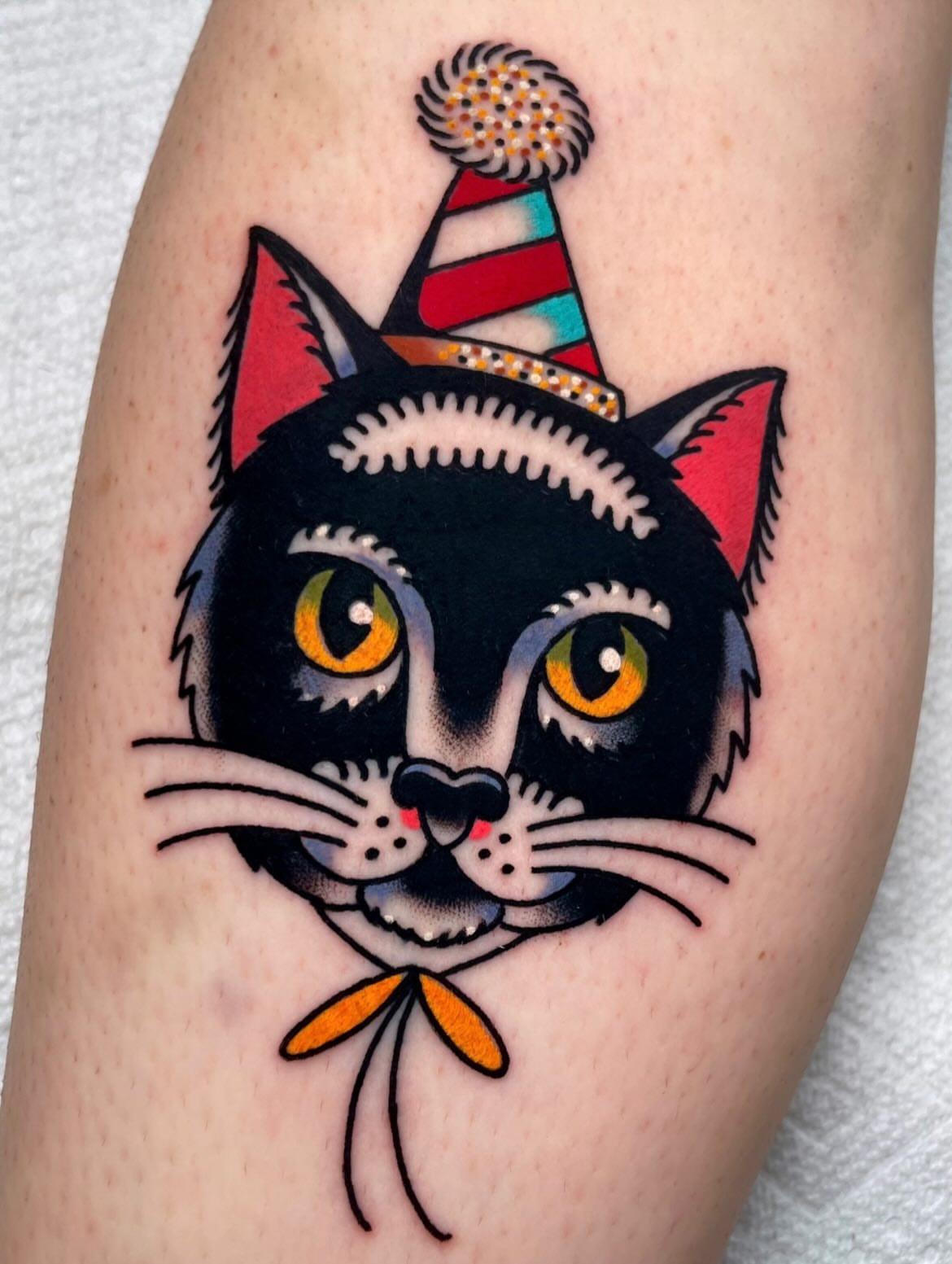 Cat wearing party hat American traditional tattoo on the forearm by Ryan McDonald
