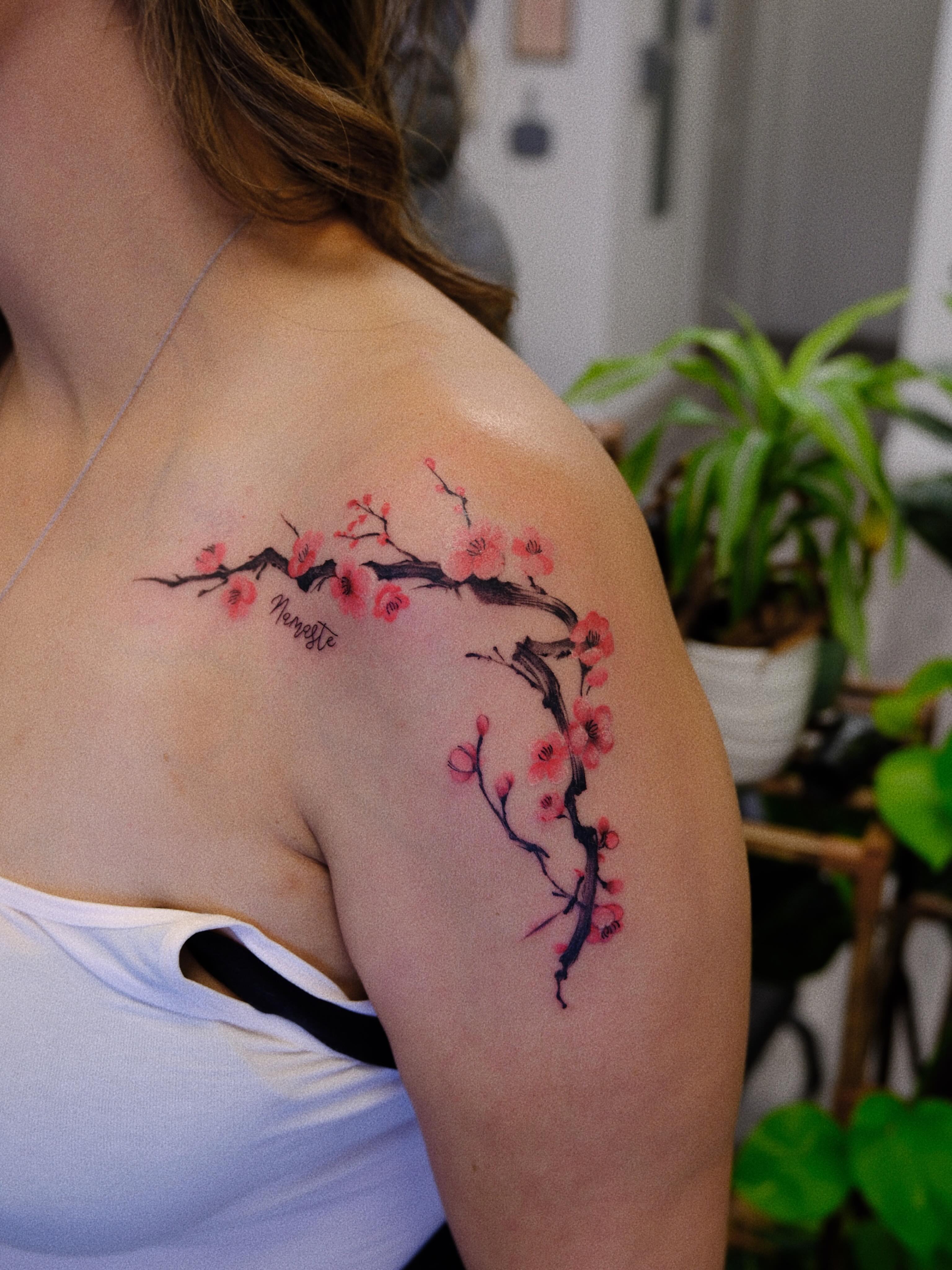 Cherry blossom branch watercolor tattoo on the shoulder by rita_tattooist