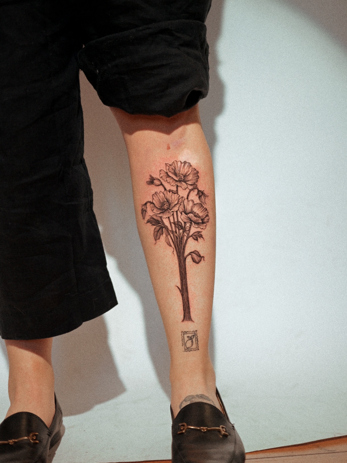 Flower bouquet black and grey tattoo on the calf by Brad Simmons