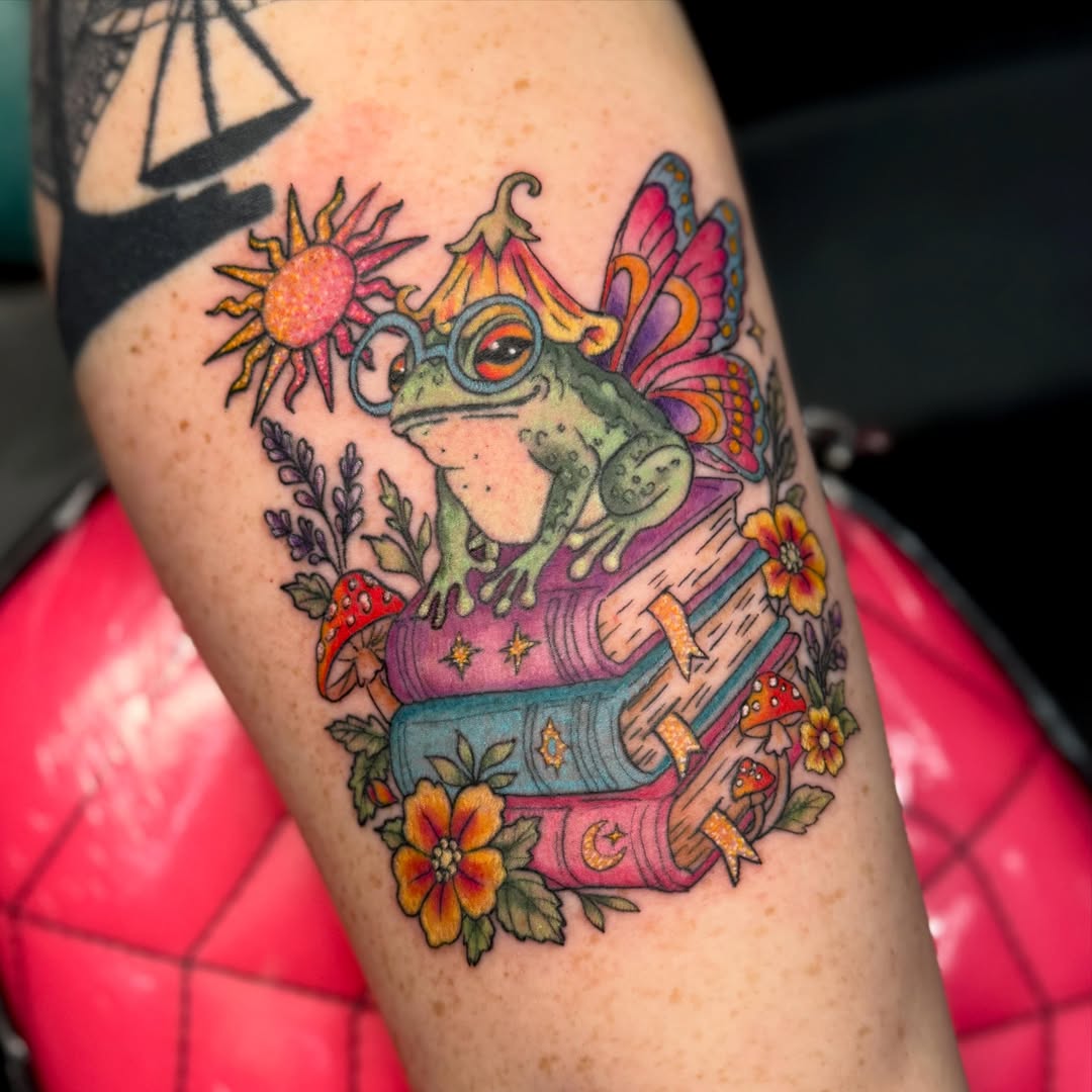 Frog with books new school tattoo on the forearm by Jada Reynolds