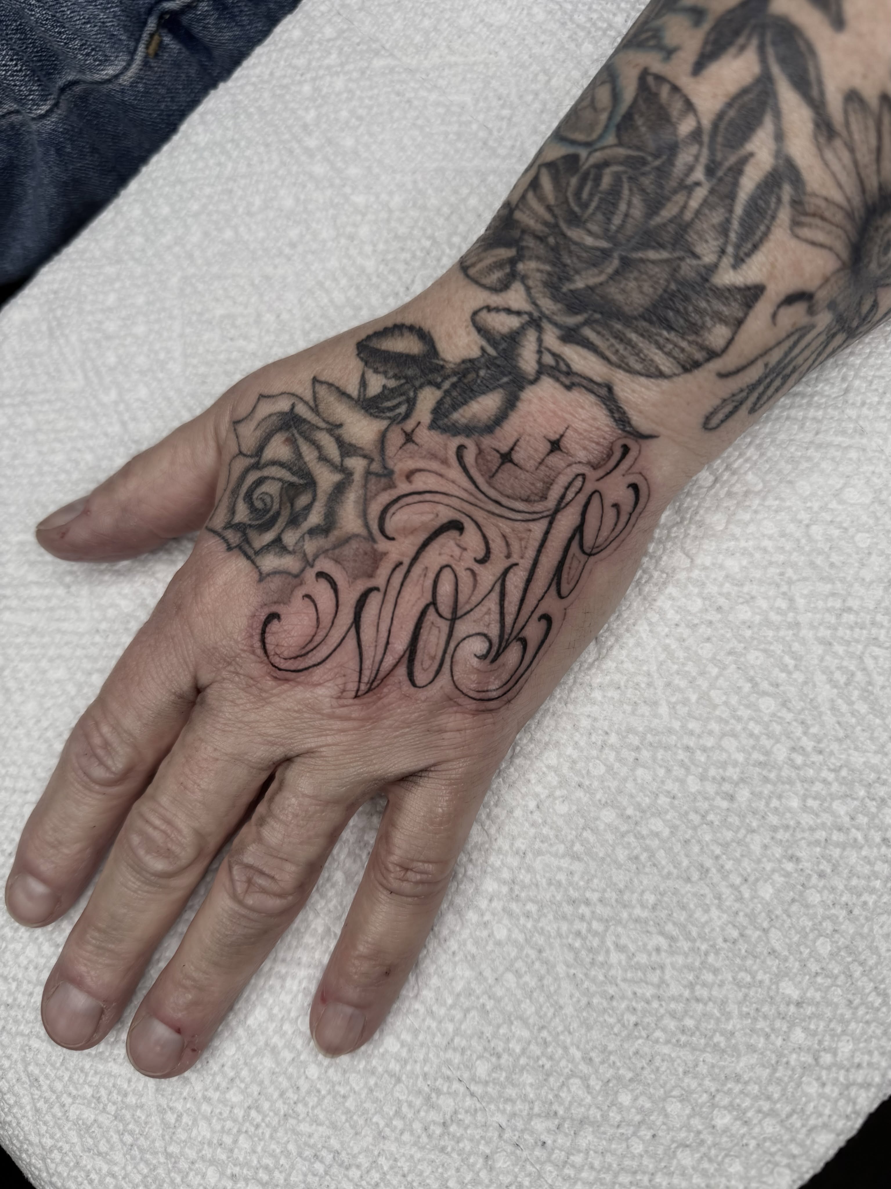 Roses and script fine line tattoo on the hand by Joe Weber, Monona, Wisconsin