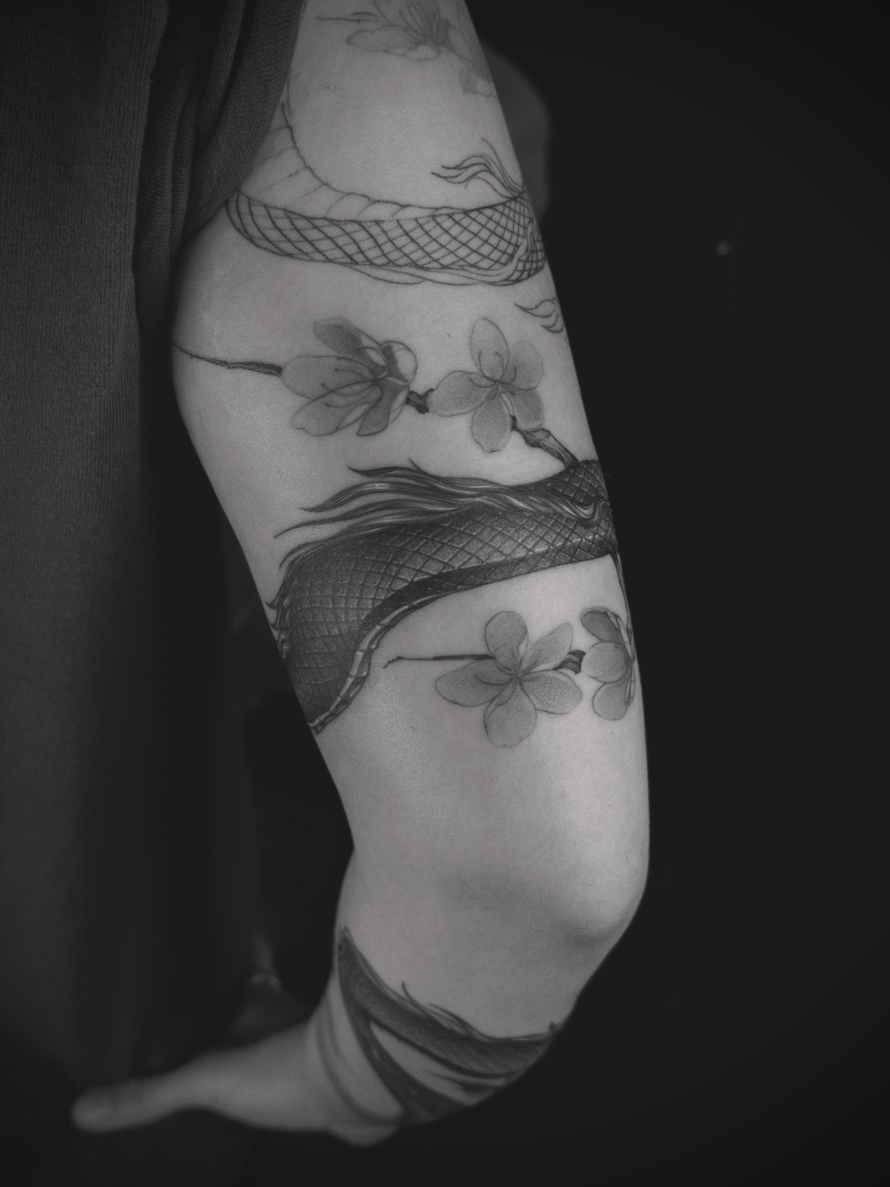 Dragon and cherry blossoms realism tattoo on the forearm by Wong Lee