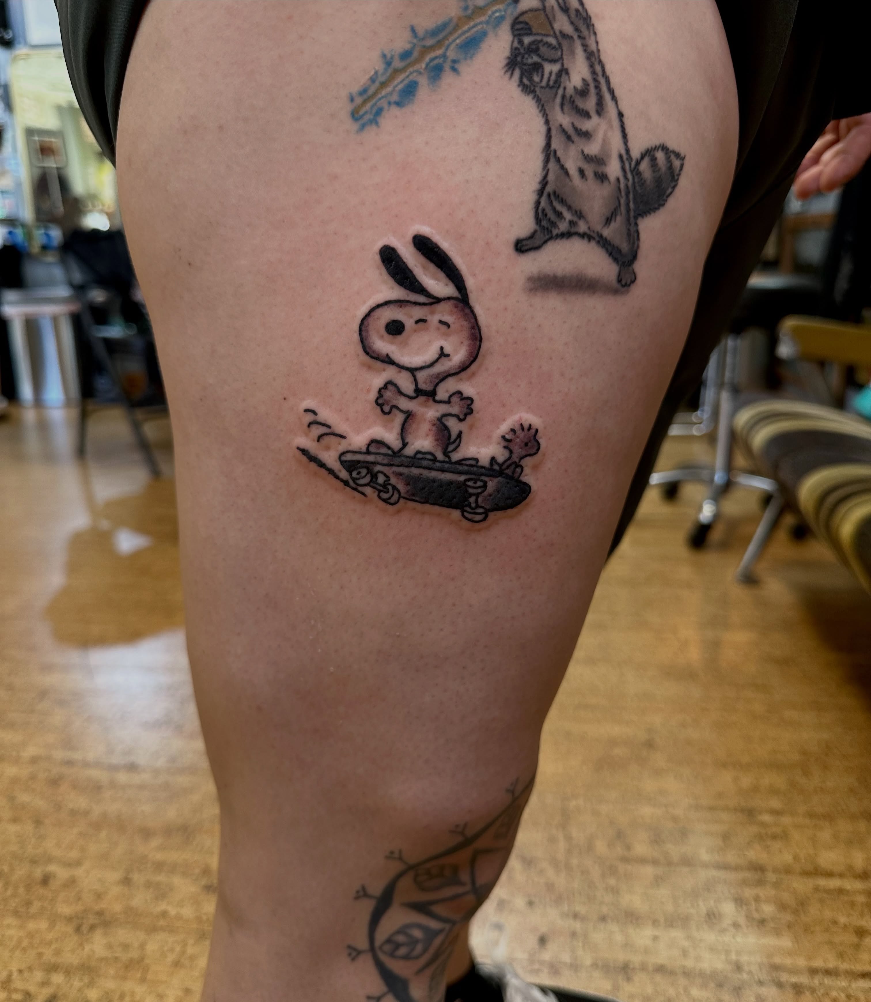 Snoopy skateboarding black and grey tattoo on the thigh by teddy, Portland, Oregon