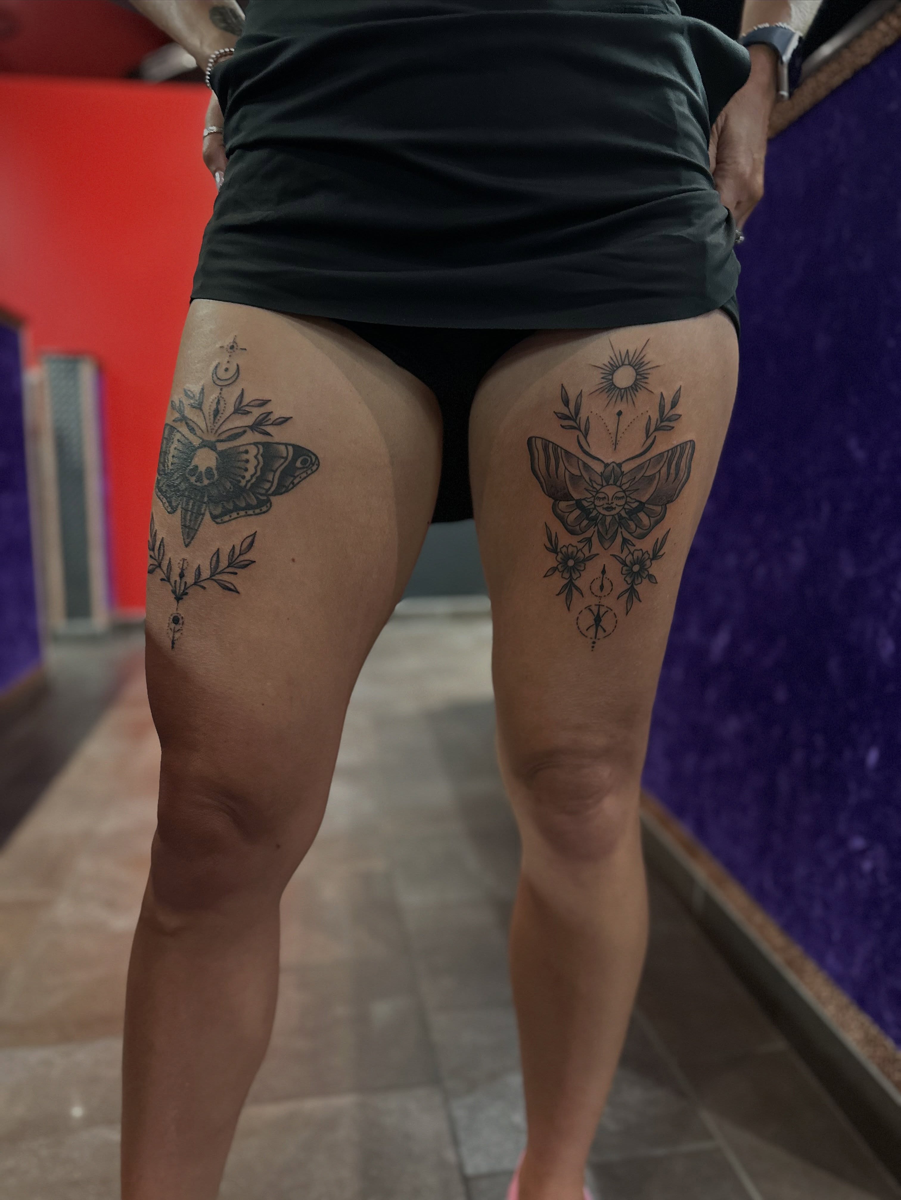 Butterfly and floral black and grey tattoo on the thigh by Walk-in American Traditional Tattoos Las