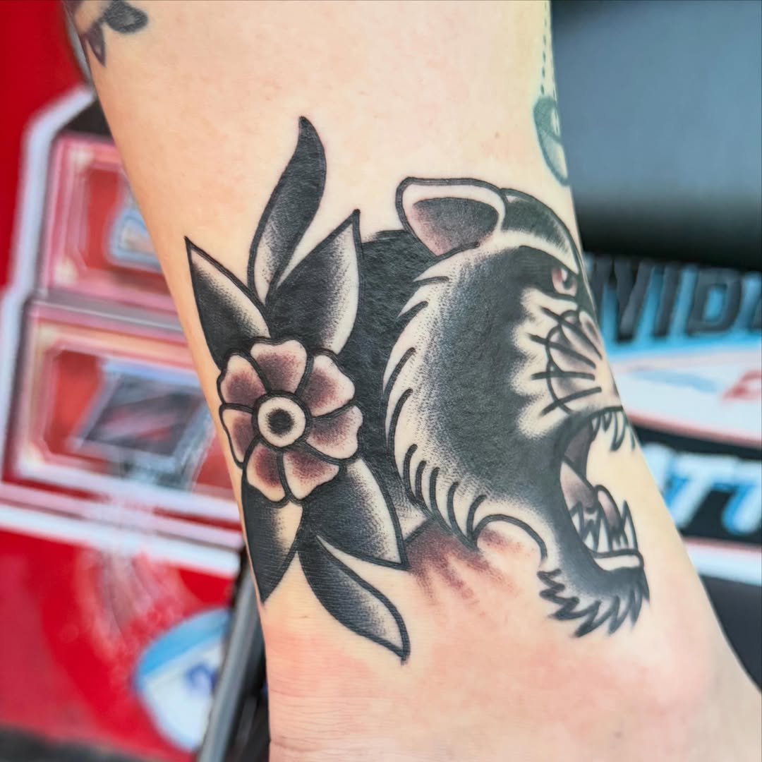 Roaring tiger with flower American traditional tattoo on the forearm by Max mogstad