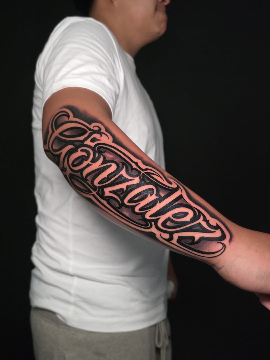Script lettering lettering tattoo on the forearm by Lukasz Olszanski