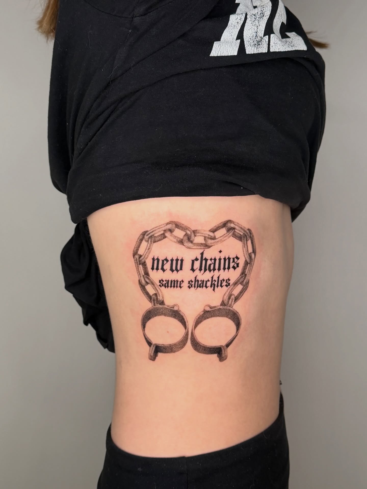 Handcuffs and chains black and grey tattoo on the ribs by Jerm Lewis